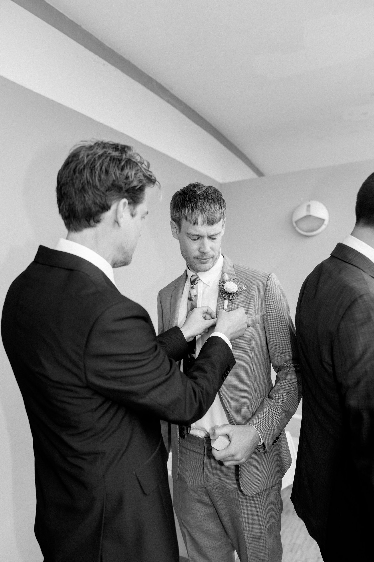 Groomsmen share a lighthearted moment while adjusting their ties before the wedding ceremony.