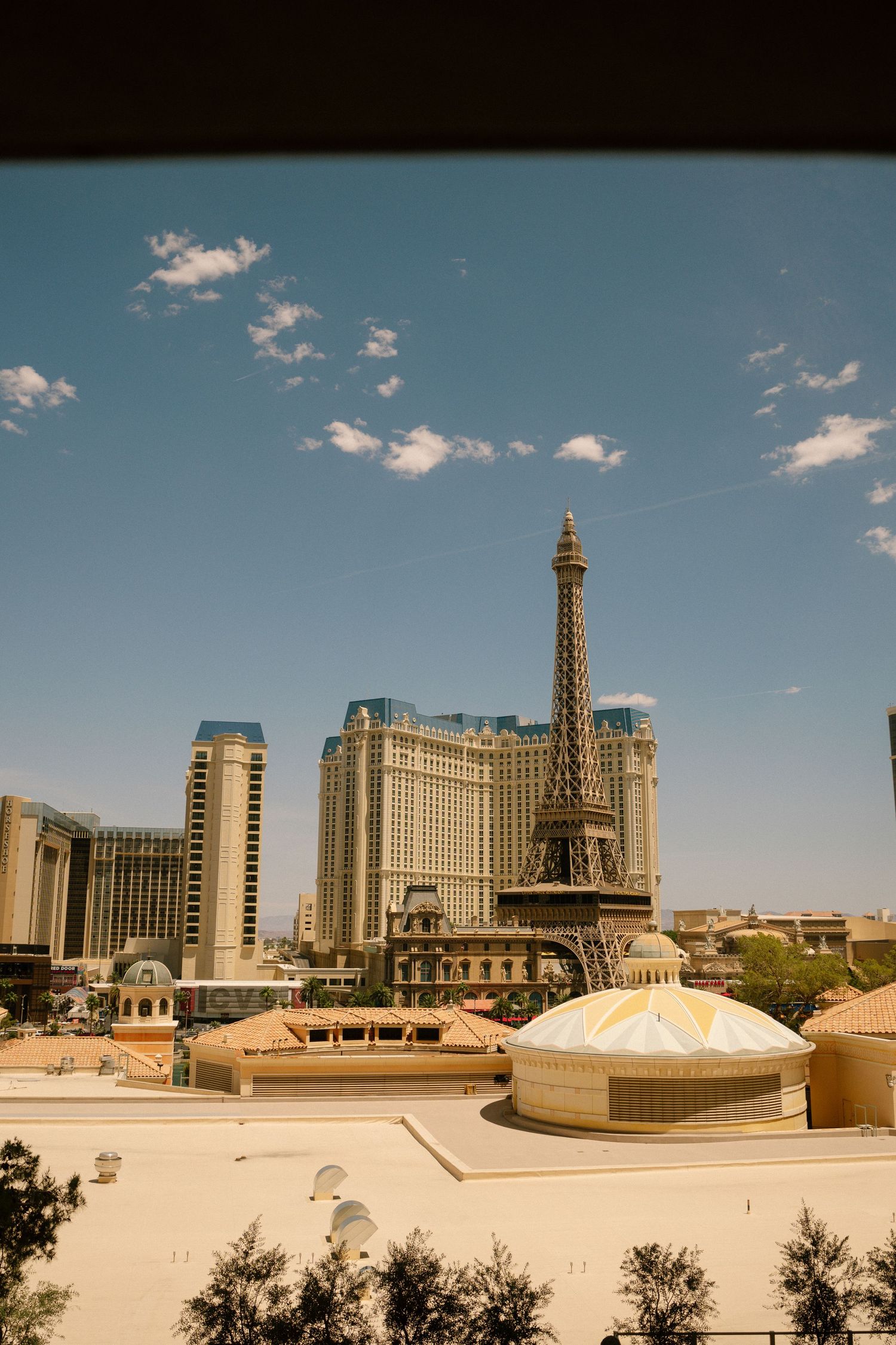 Paris Las Vegas Hotel and Casino with Eiffel Tower replica against bright blue desert sky.