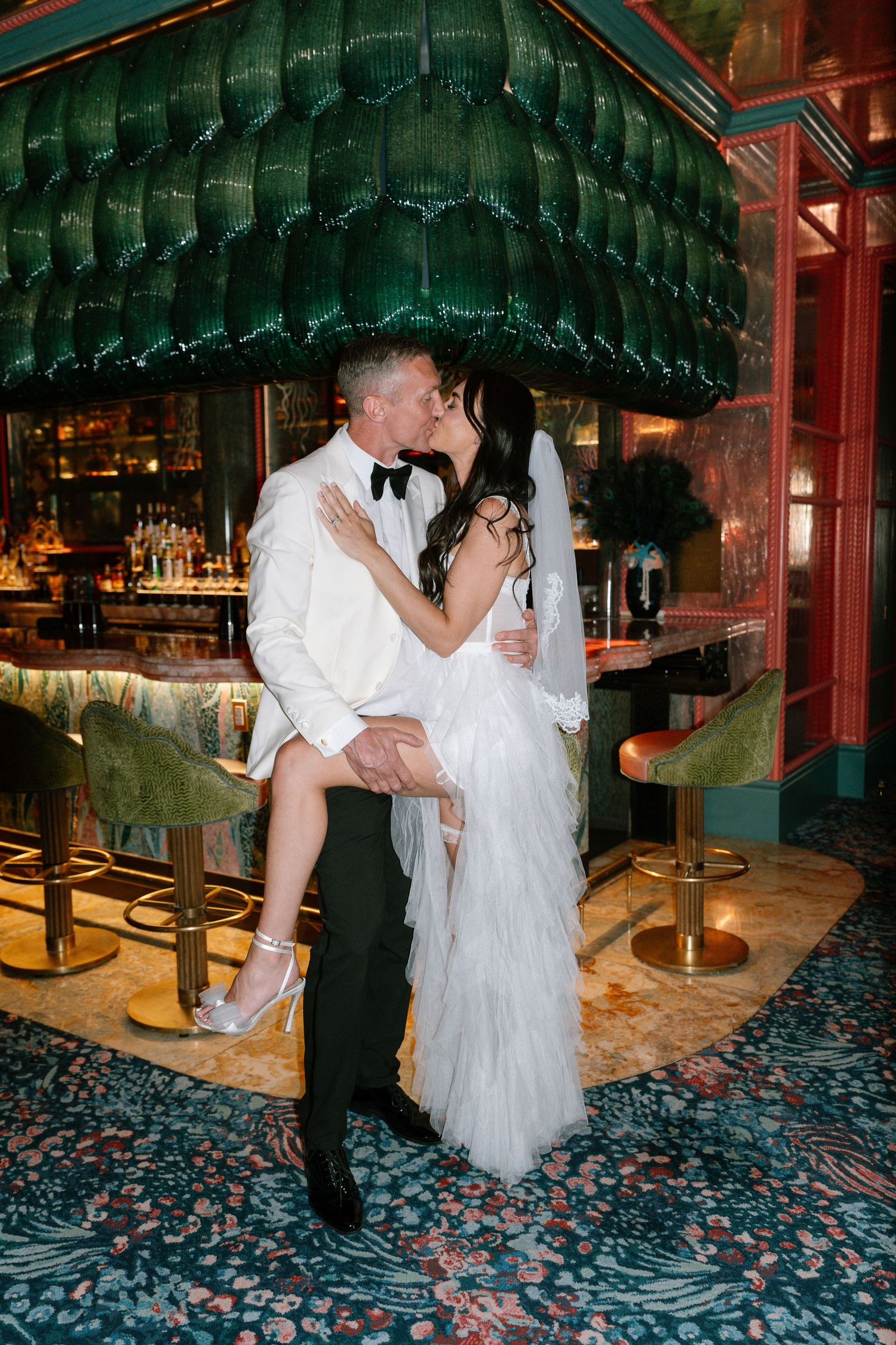 A couple dances romantically beneath green decor at an elegant venue.