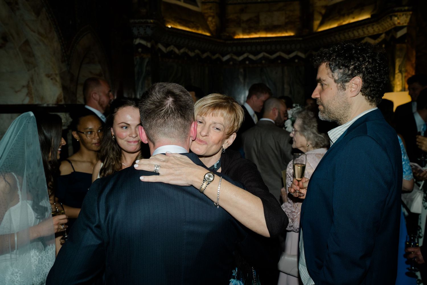 Wedding guests share warm embraces and celebrate during a lively wedding reception party.