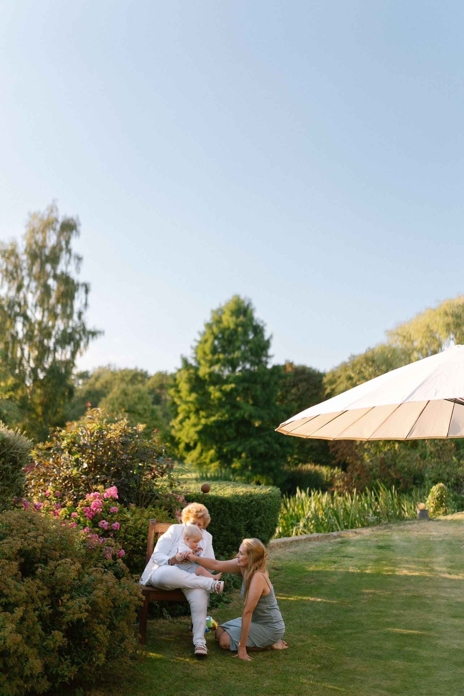 A tender moment shared between figures lying in a lush green garden on a bright summer day.