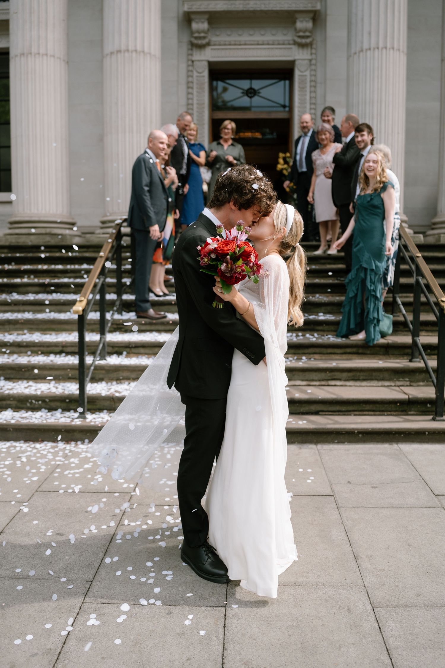 Couple dances together during confetti celebration on grand building steps.
