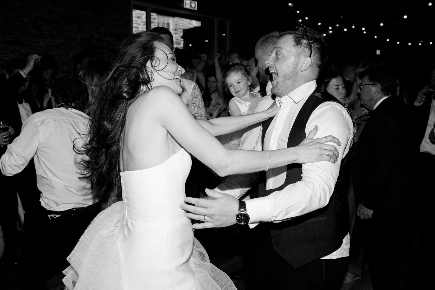 Wedding guests dancing and celebrating on the dance floor at a reception.