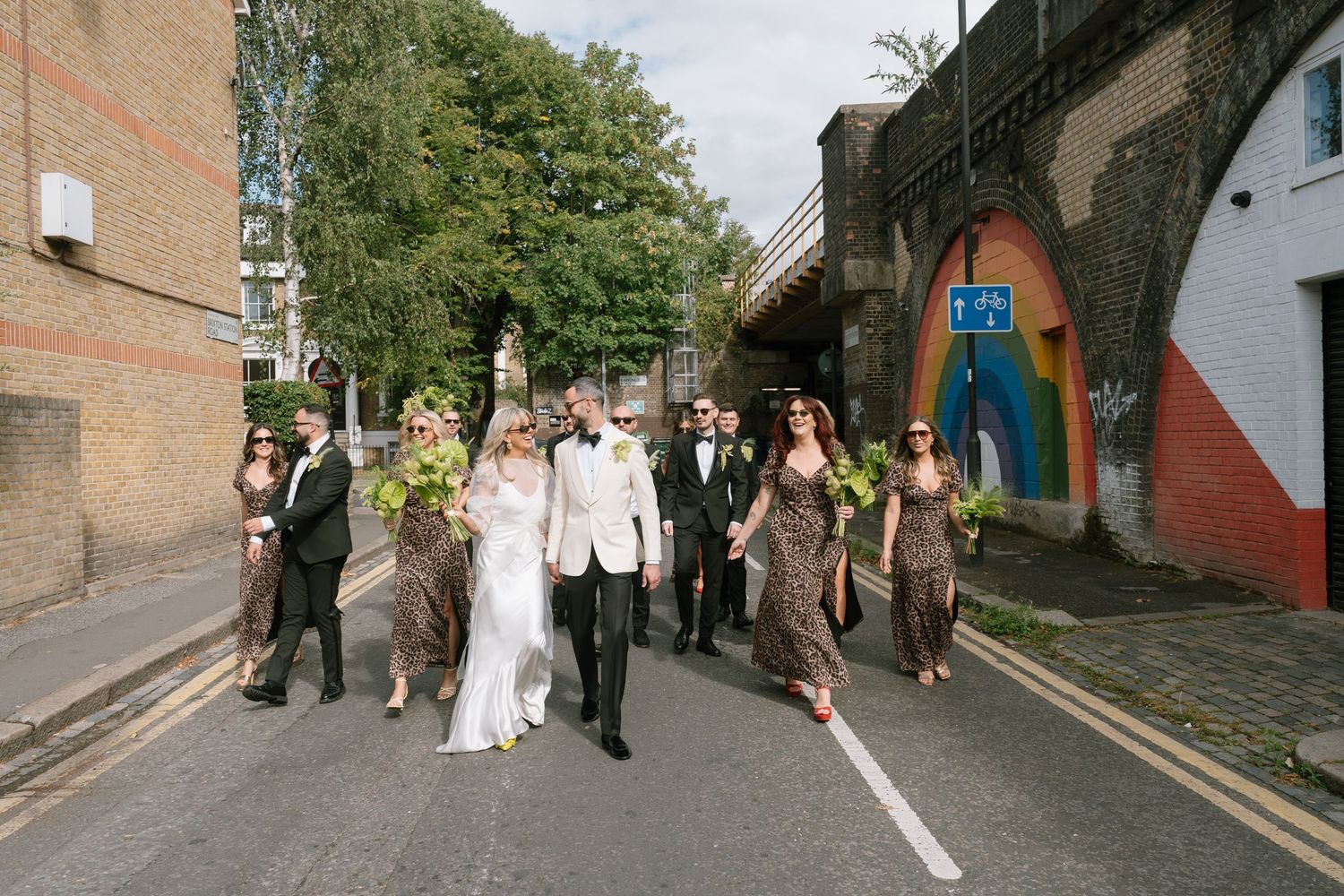 Wedding party walking down urban street in formal attire.