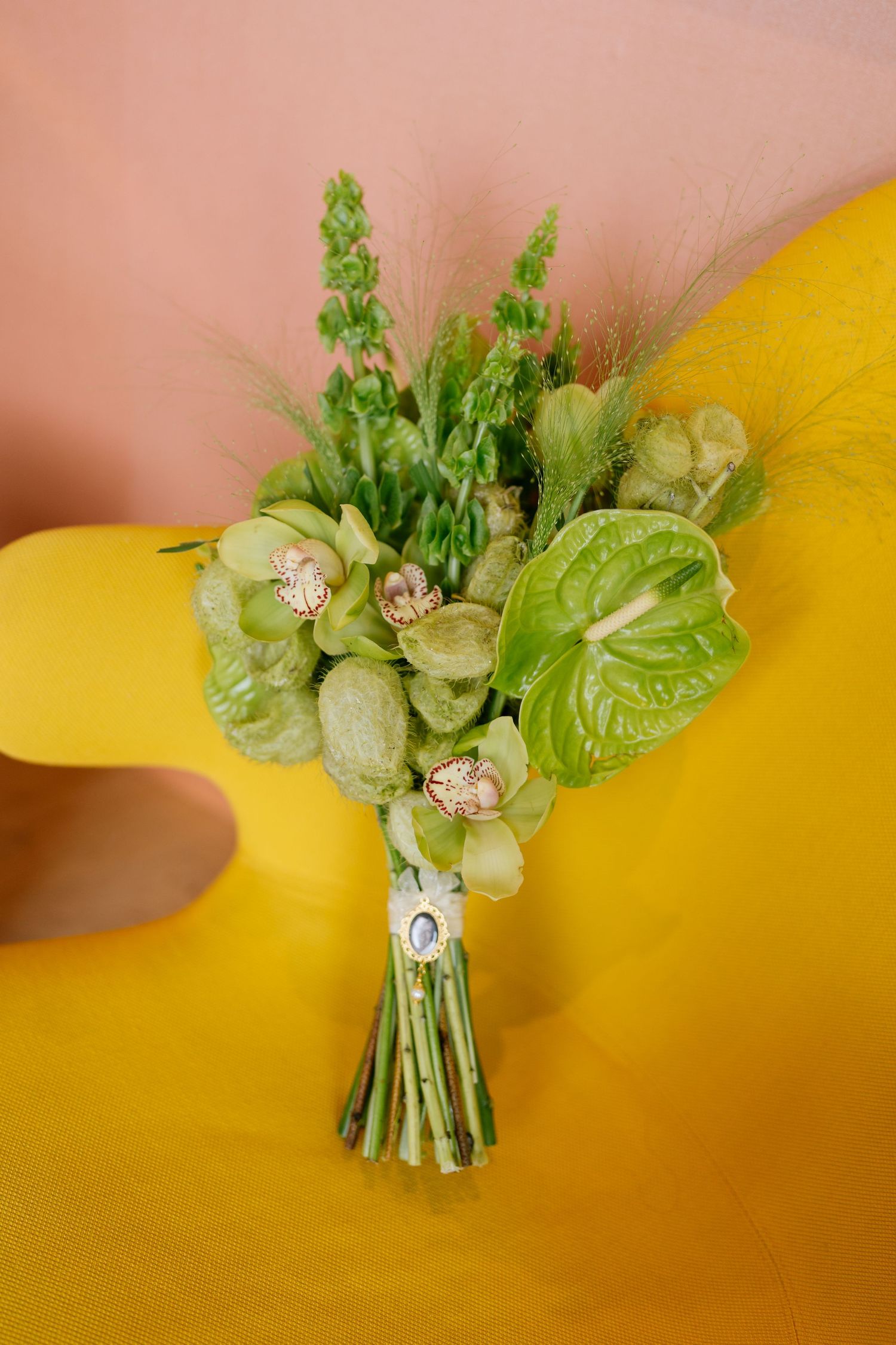 Small floral bouquet with green foliage and white flowers against a warm yellow background.