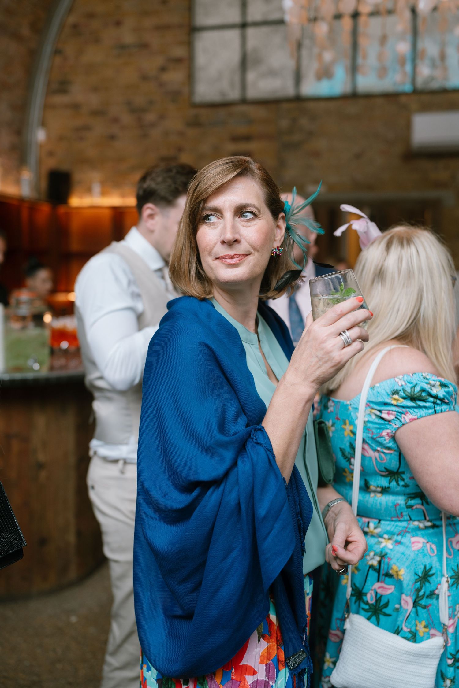 Wedding guests in blue and turquoise outfits mingling at reception.