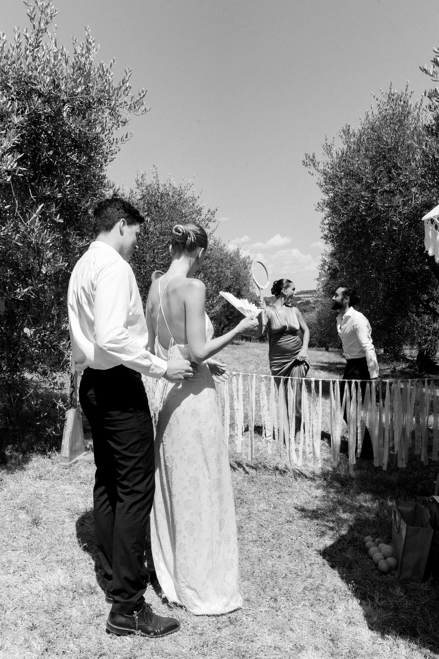 People enjoying an outdoor gathering in a garden setting with white picket fence.