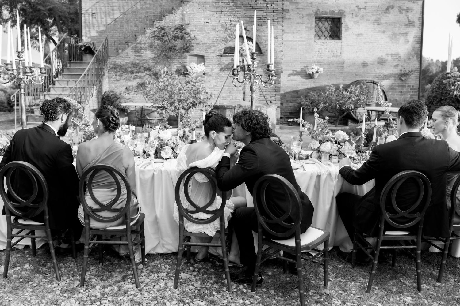 Black and white photo of wedding guests seated at outdoor reception tables.