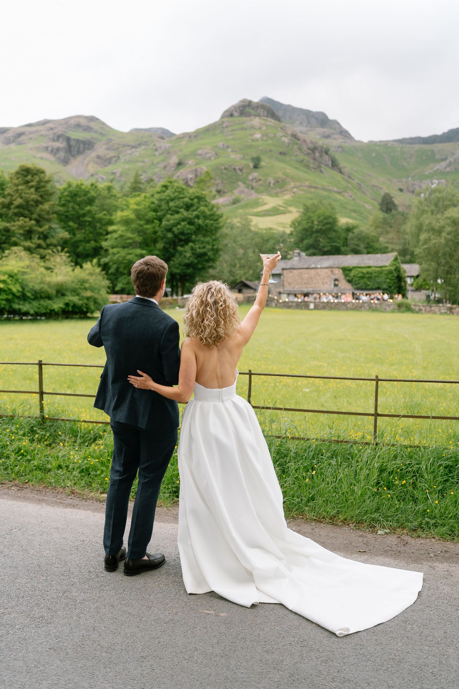 Couple walking along countryside path with mountain views in background.