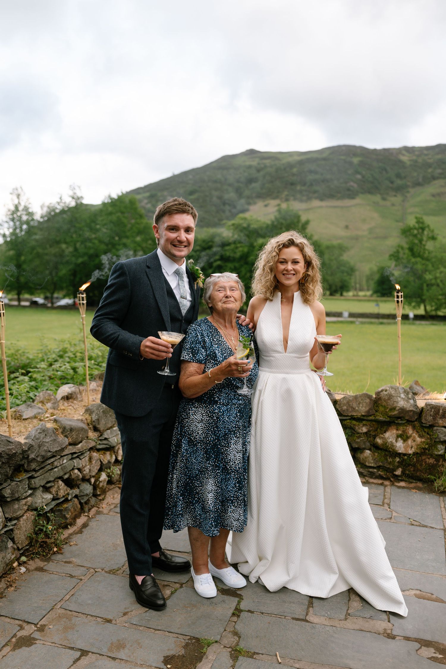 Wedding photo with mountain backdrop and stone wall in the foreground.
