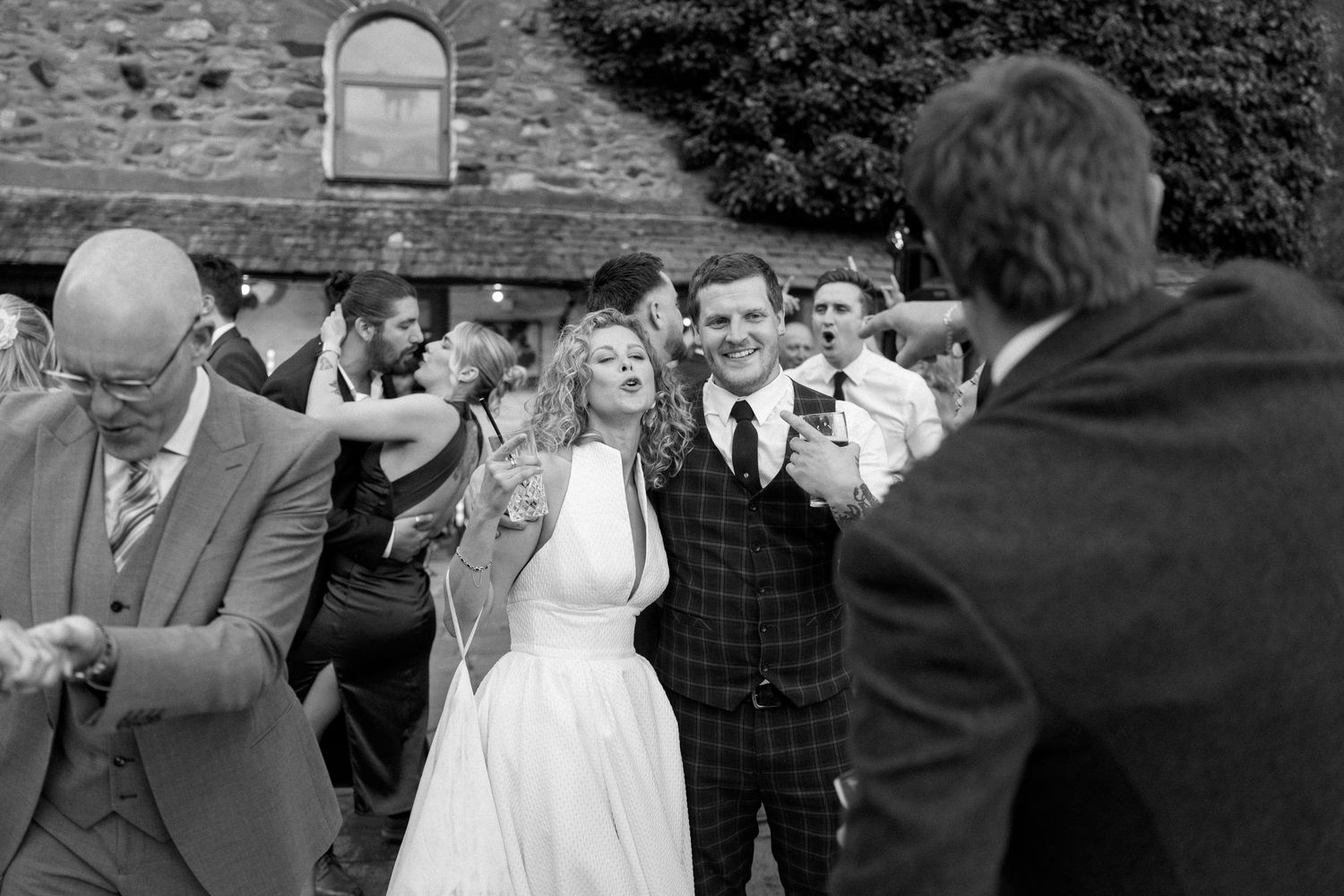 Wedding party celebrating with dancing and festivities on a stone patio.