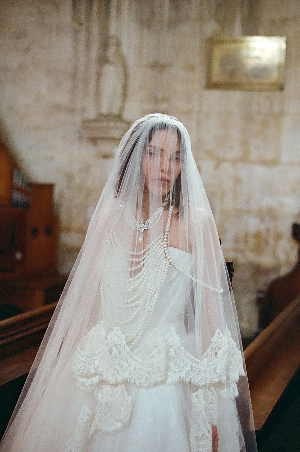 A delicate bridal veil adorned with pearls and lace details drapes elegantly in soft lighting.