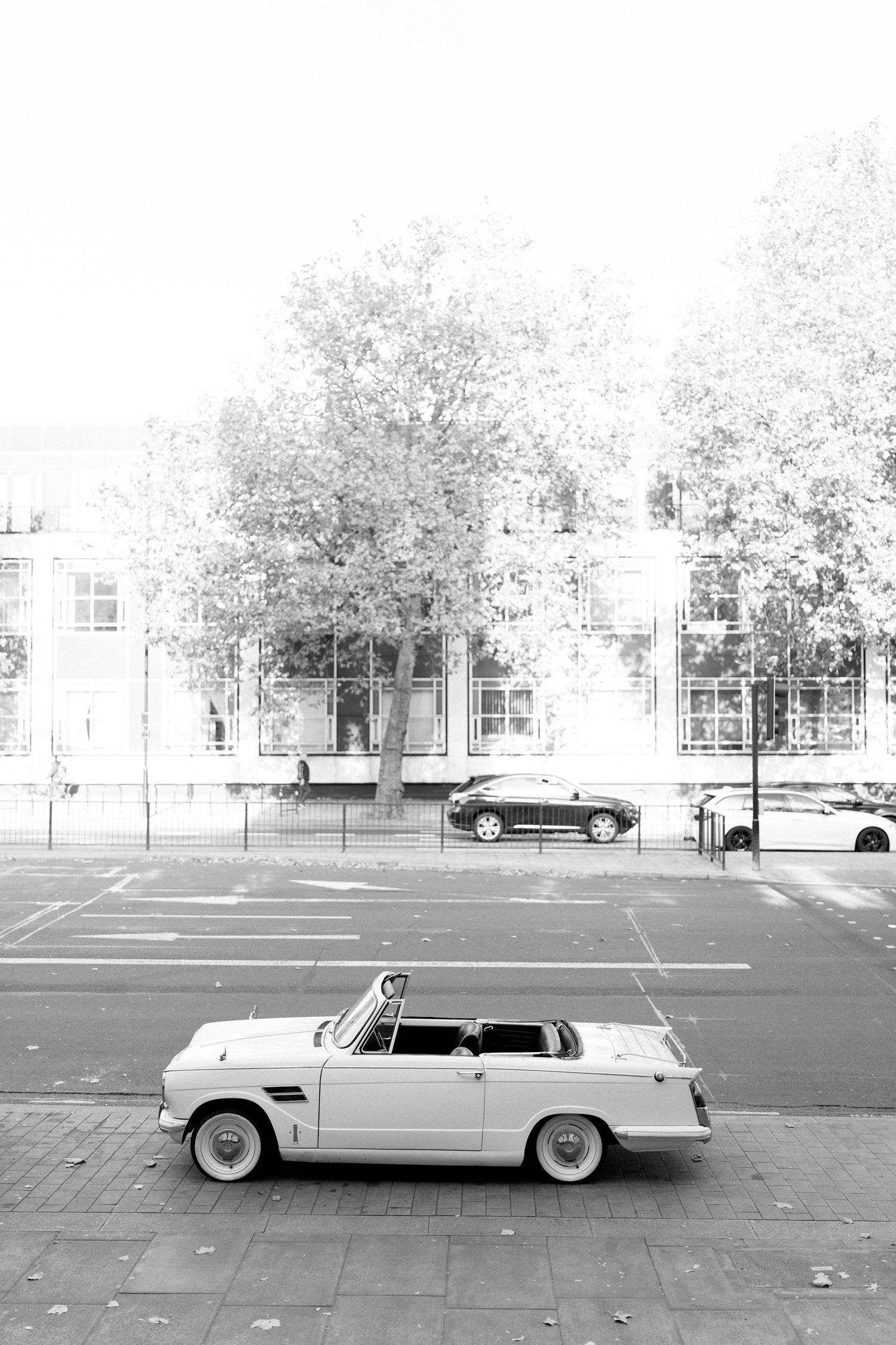 Classic white convertible car parked in front of historic building in black and white photography.