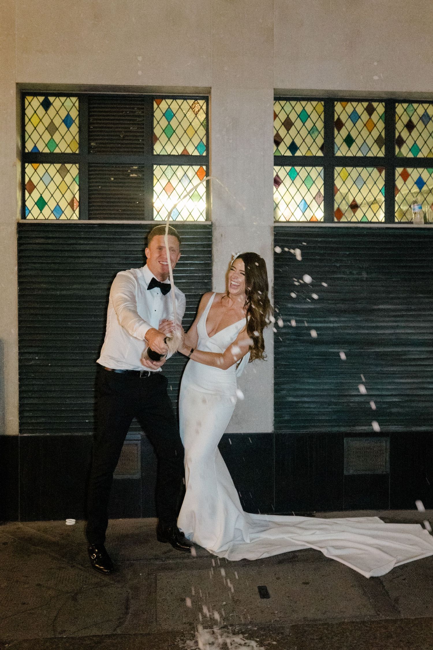 Dancing couple in formal attire with stained glass windows in background.