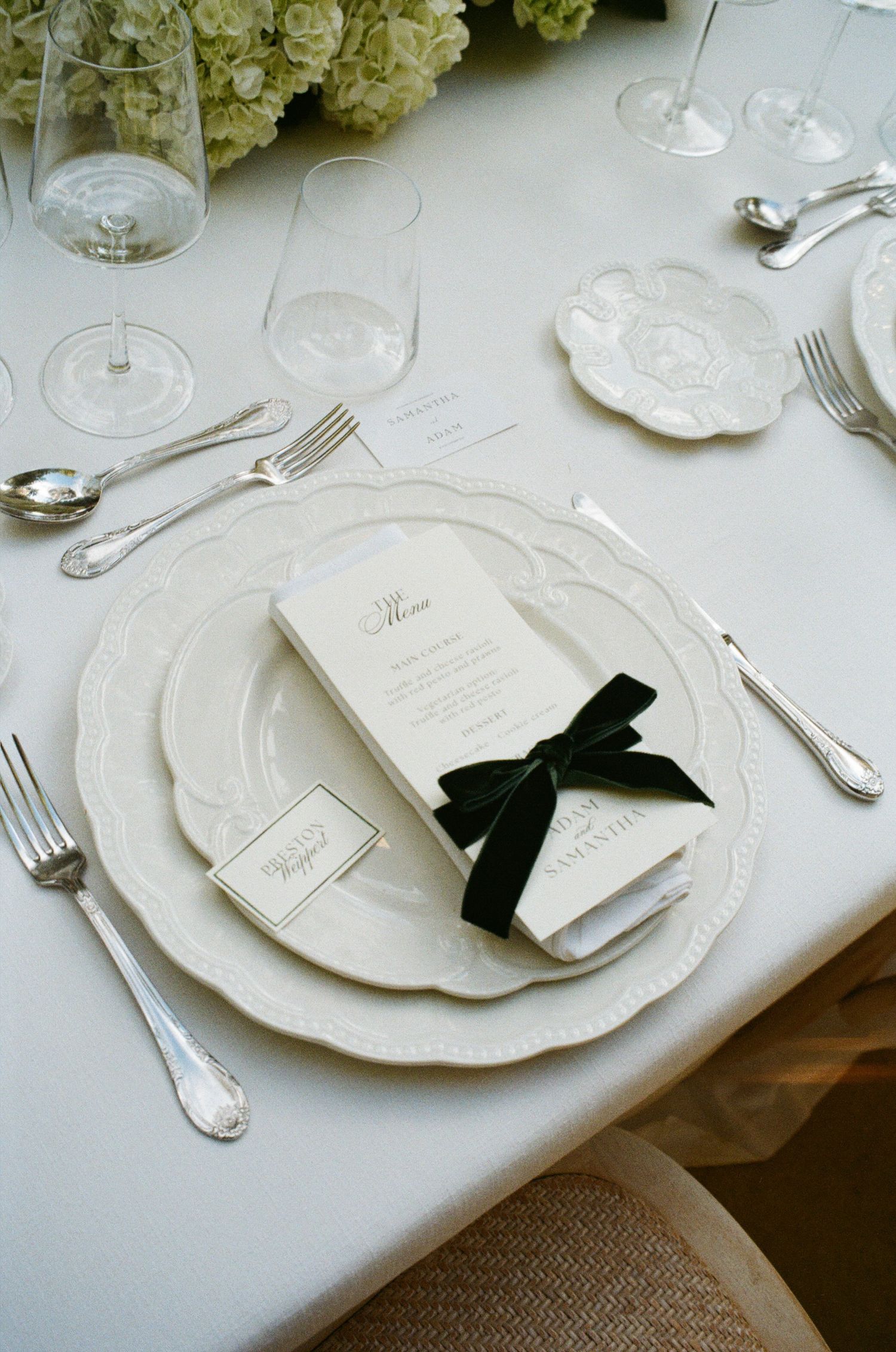 Elegant white place settings with black bow accents on a formal dining table.