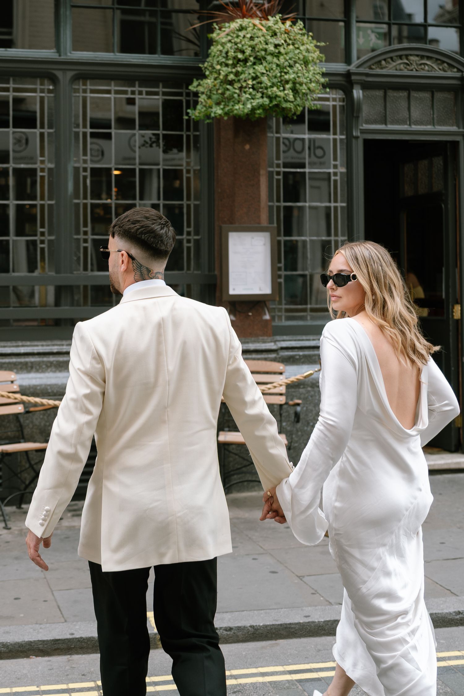 Two people in white outfits running playfully down a city street.