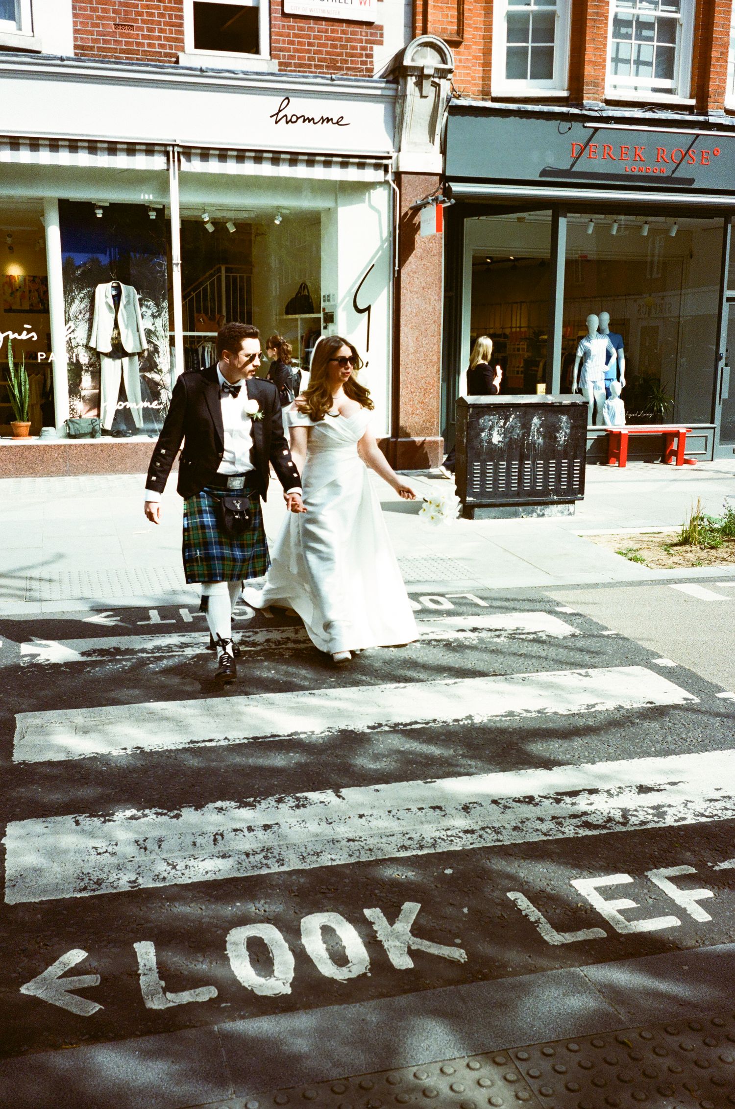 Panoramic sequence of people walking past street text reading 'LOOK LEFT' painted on asphalt in an urban setting.