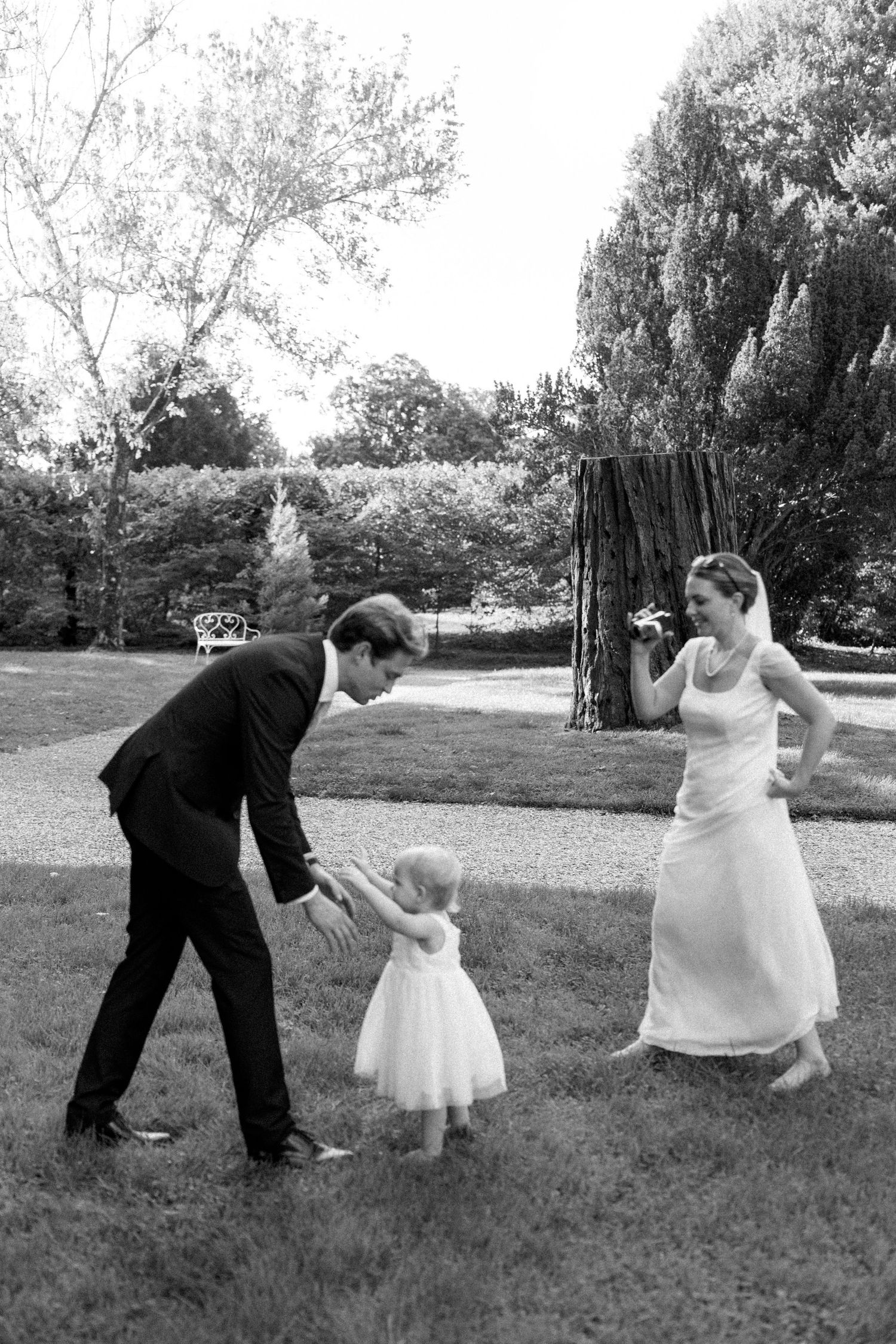 A black and white photo of a wedding celebration with dancing on a garden lawn.