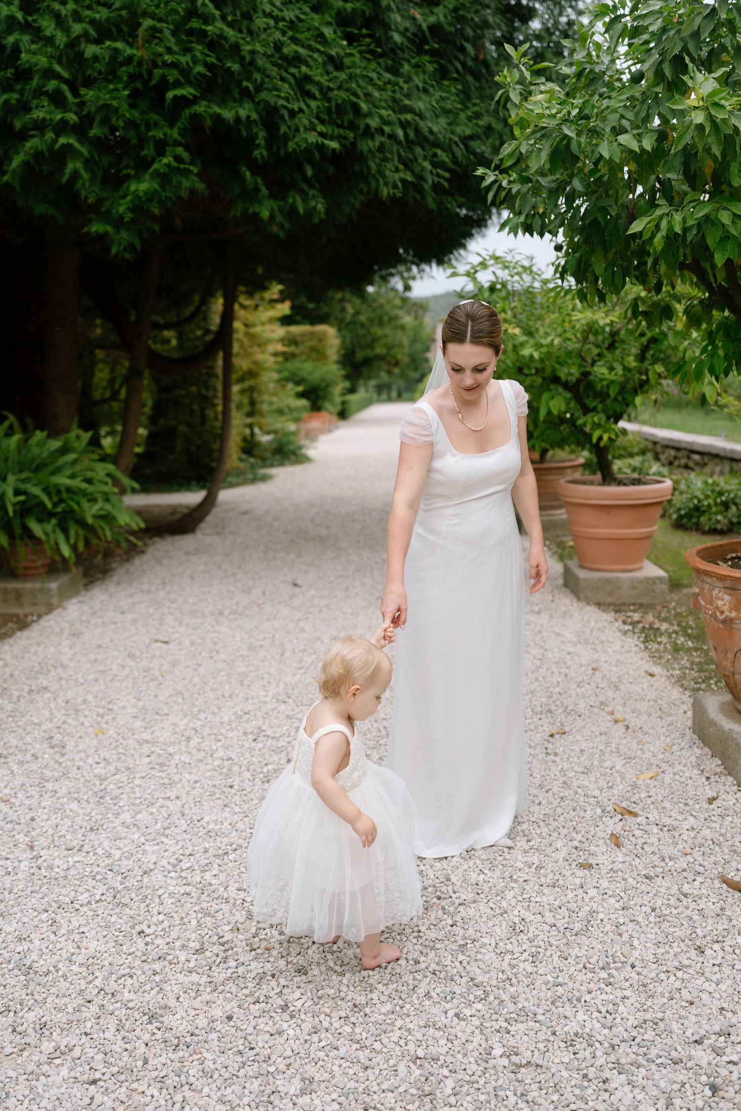 A tender moment captured between two people walking on a white gravel garden pathway.