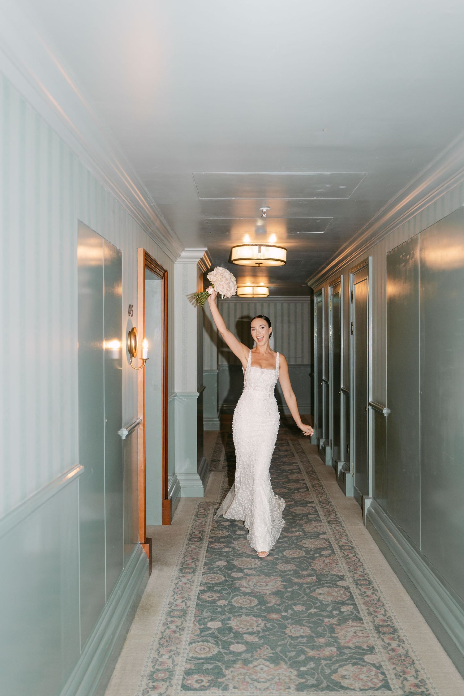 Sequence of a bride in white dress posing and dancing down a blue-walled hotel hallway.