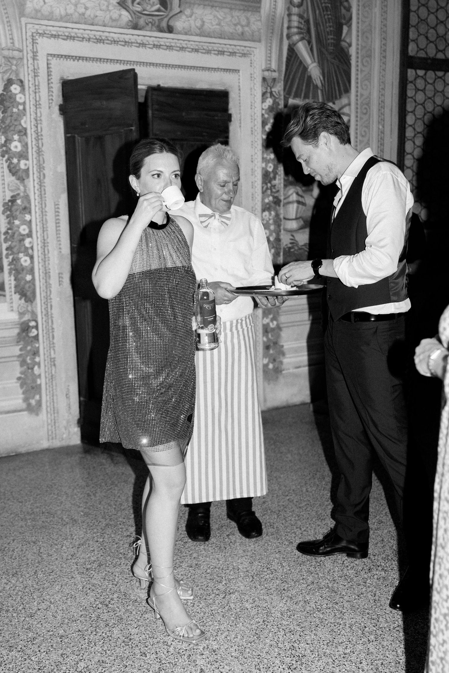 People dancing and socializing at an elegant formal event in a grand ballroom.