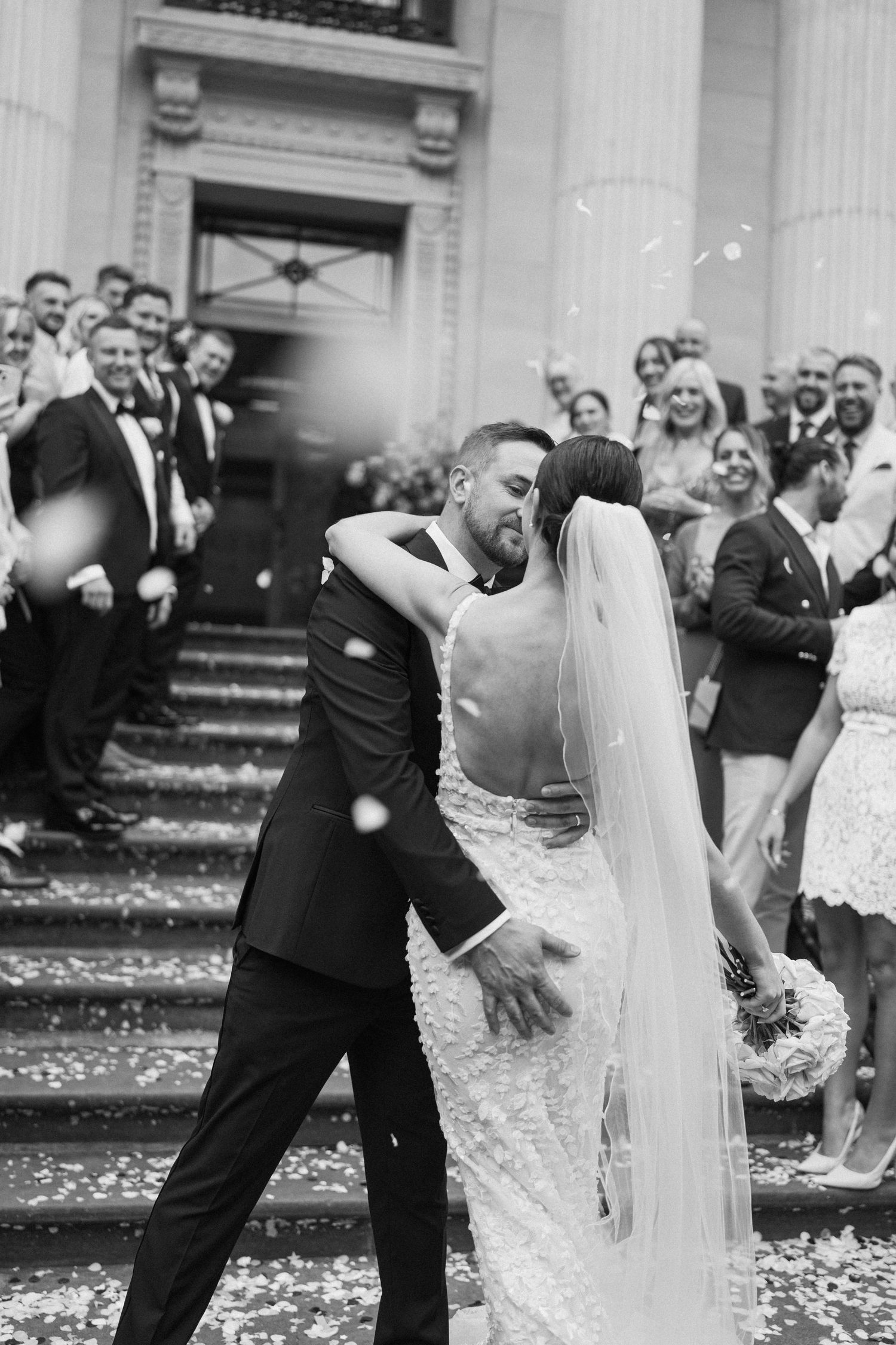 Romantic dip pose during wedding celebration with guests watching.