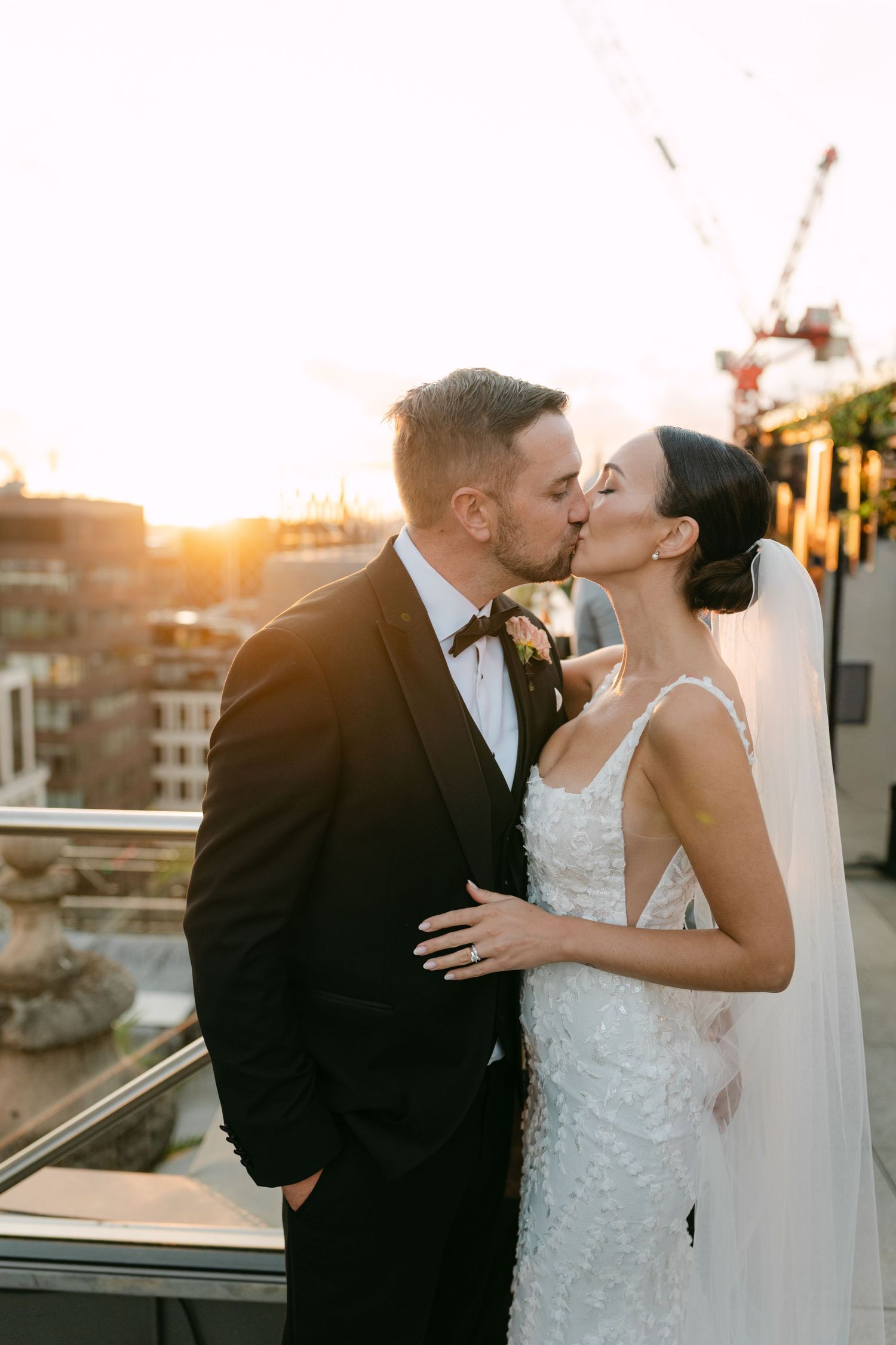 Newlyweds sharing intimate moments during sunset rooftop photo session.