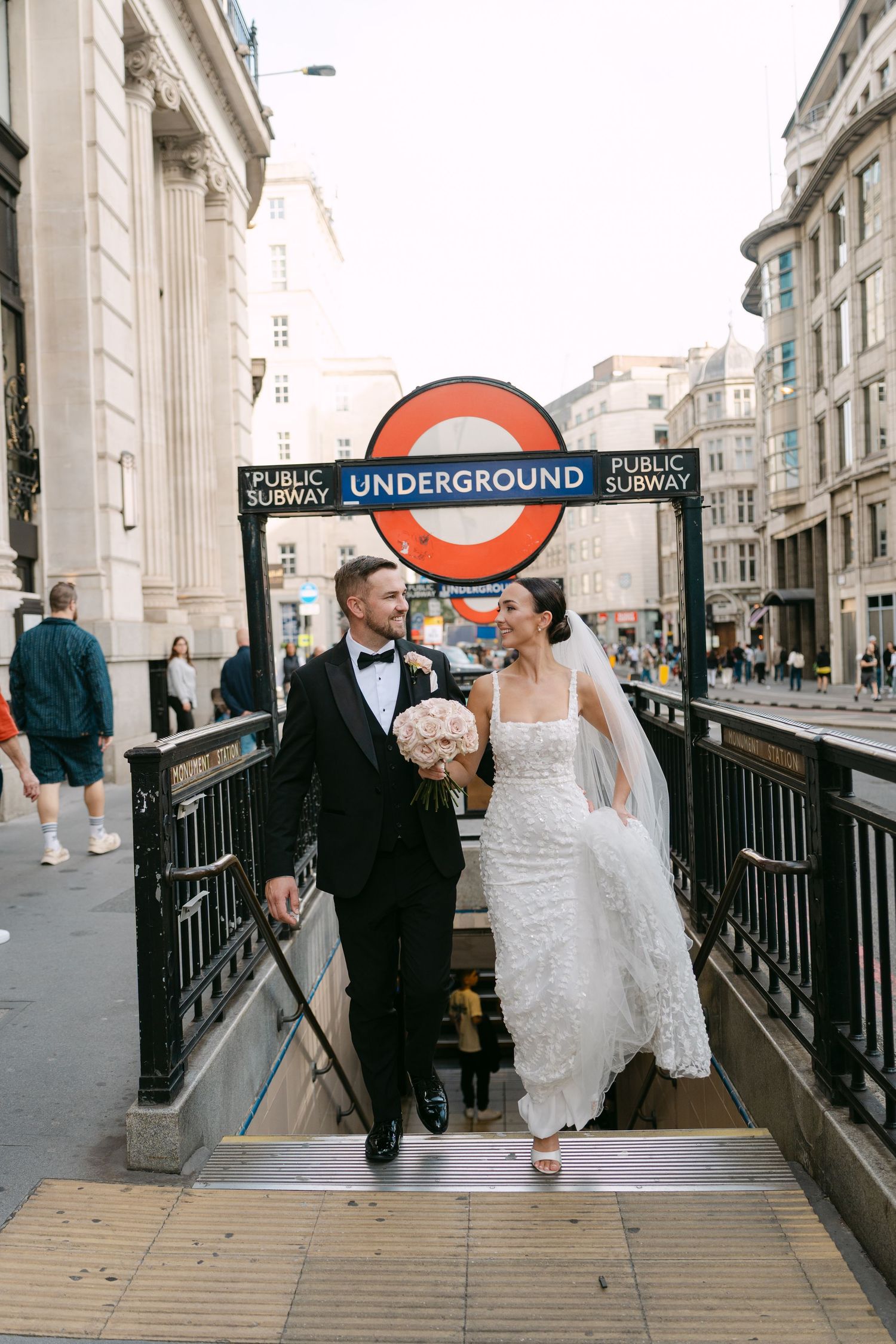 Wedding couple walking near a London Underground station entrance.