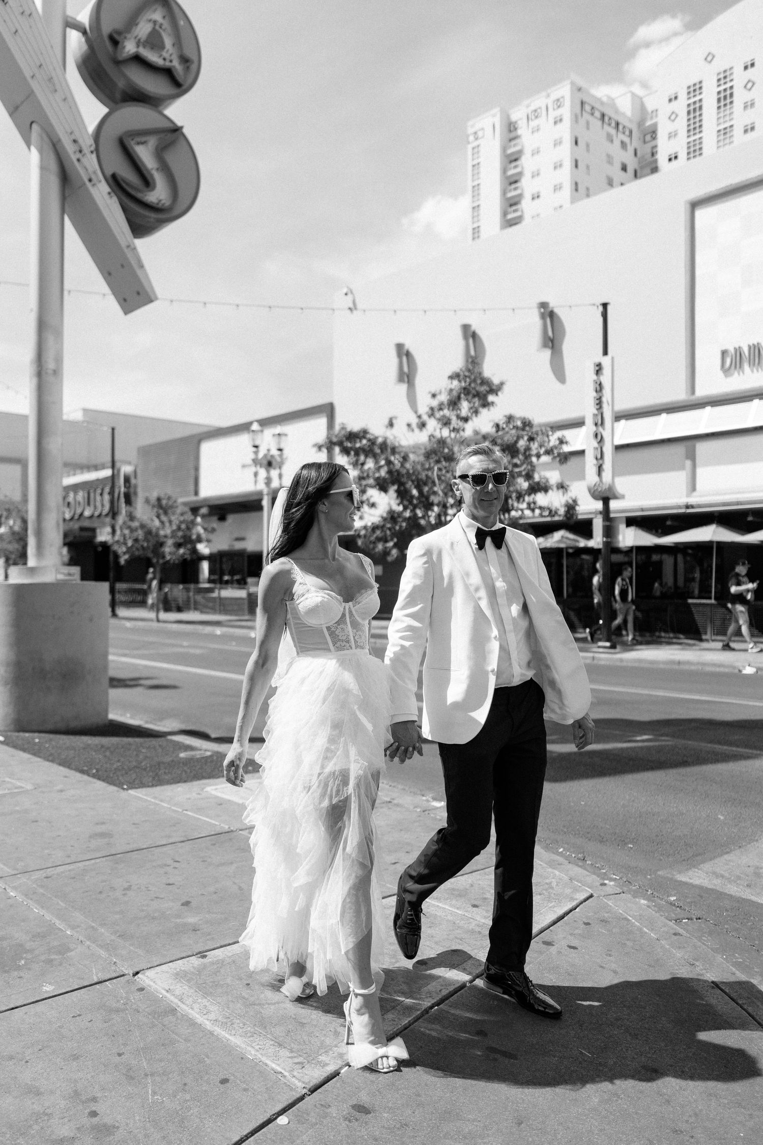 Newlyweds walking down urban sidewalk in black and white photography.