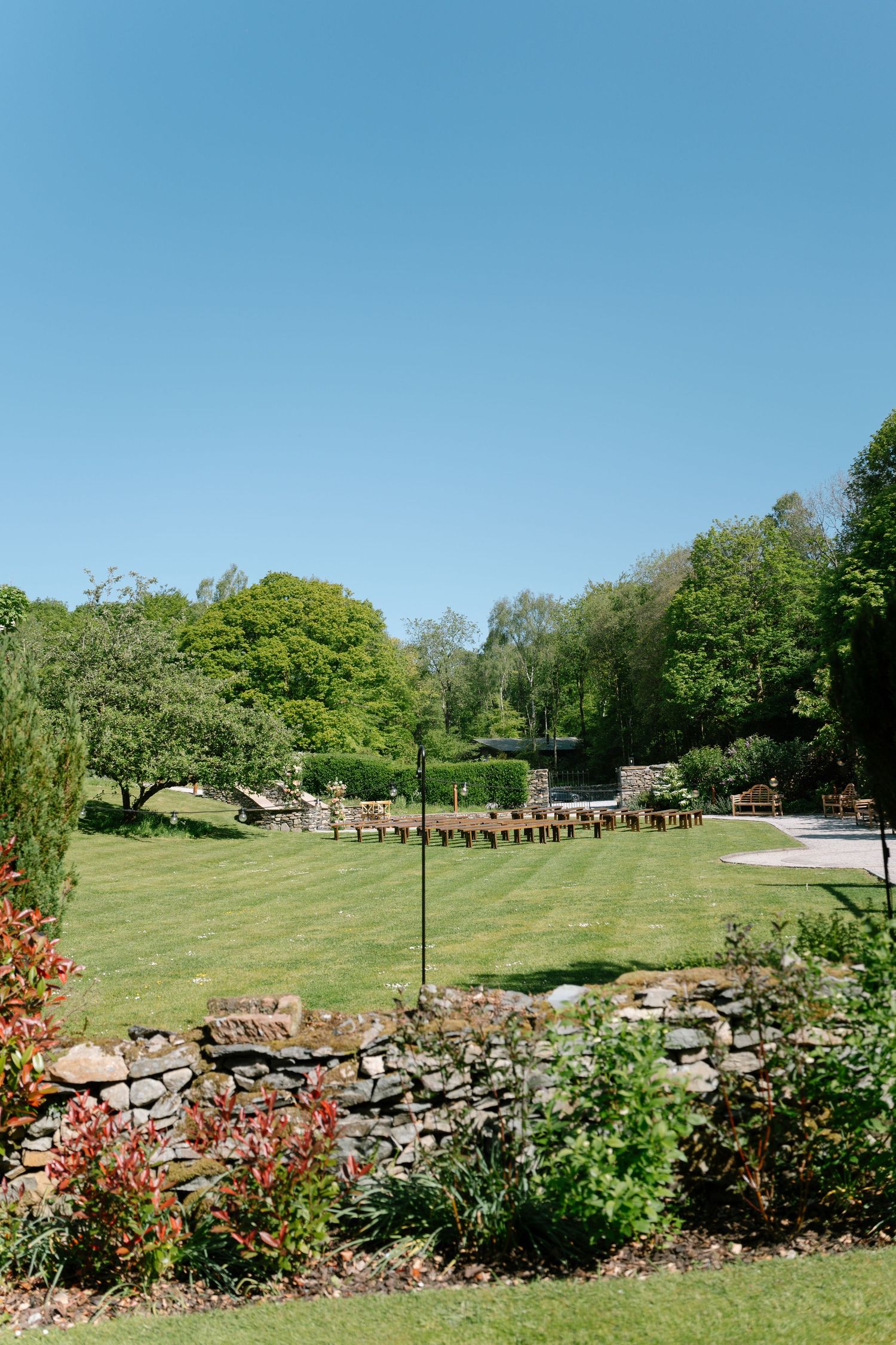Panoramic view of landscaped garden with stone wall and flowering plants.
