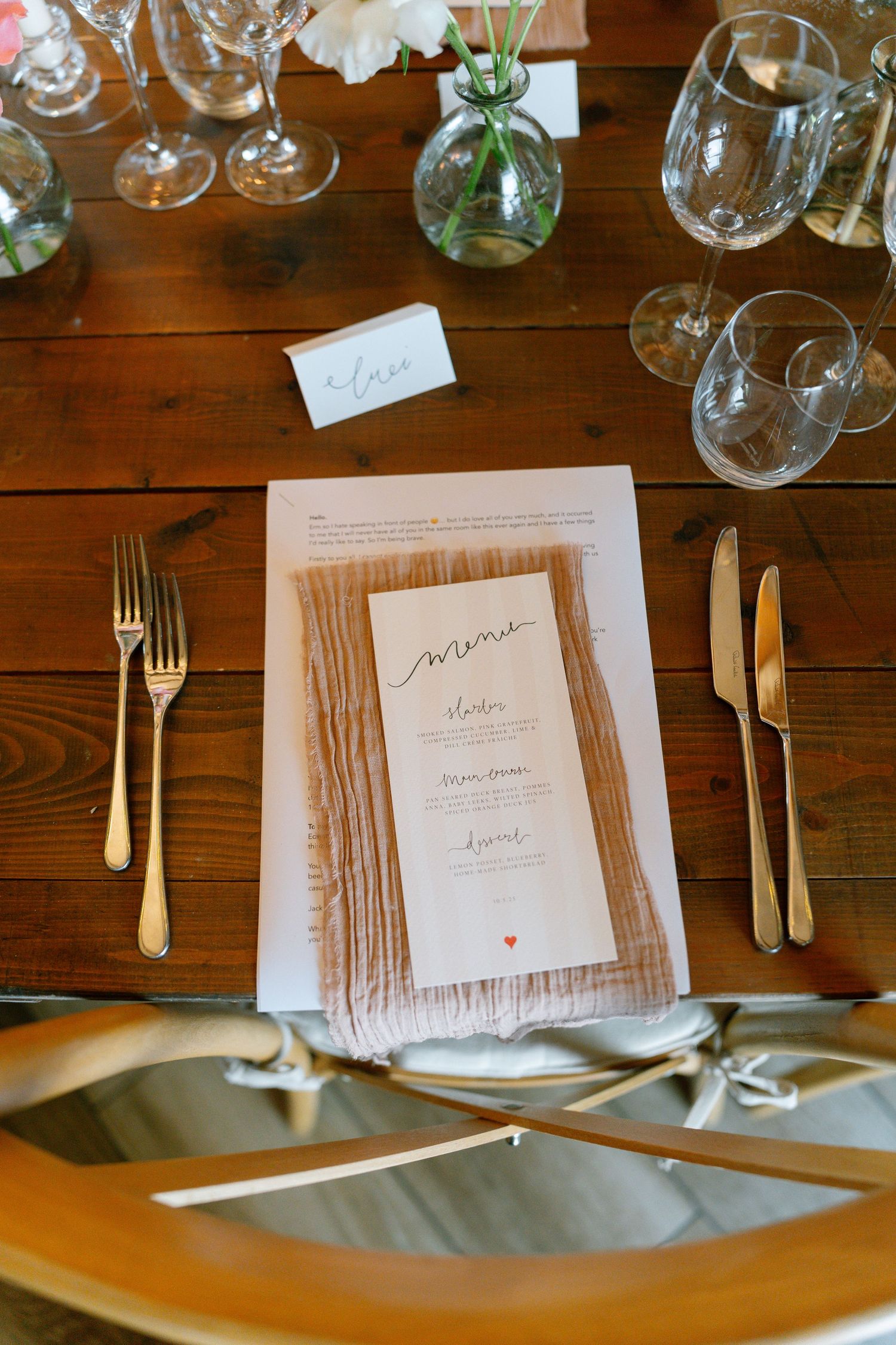 Formal table settings with white napkins, printed menus, and elegant silverware on wooden tables.