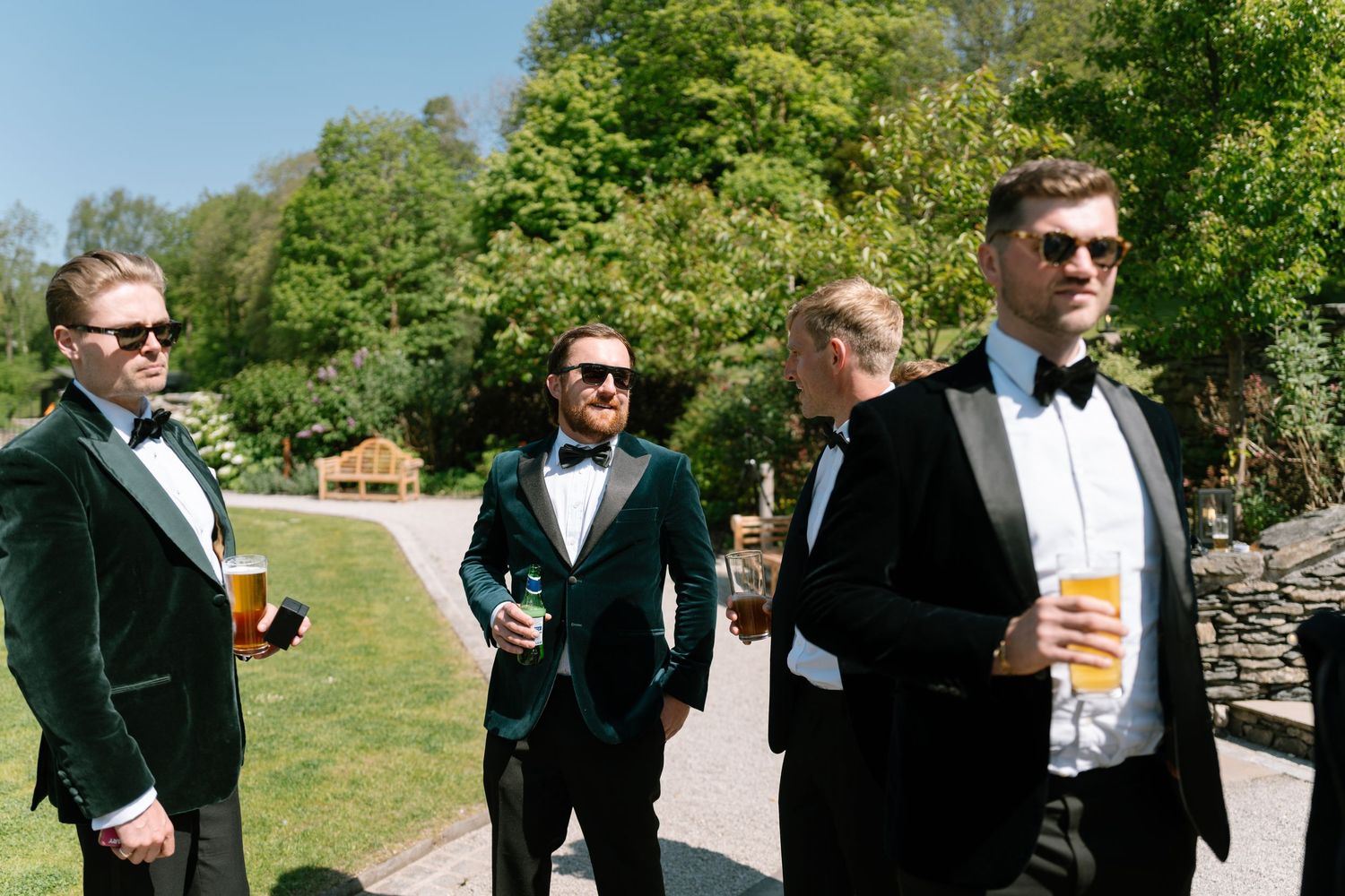 Wedding party members in formal attire socializing on a green lawn.
