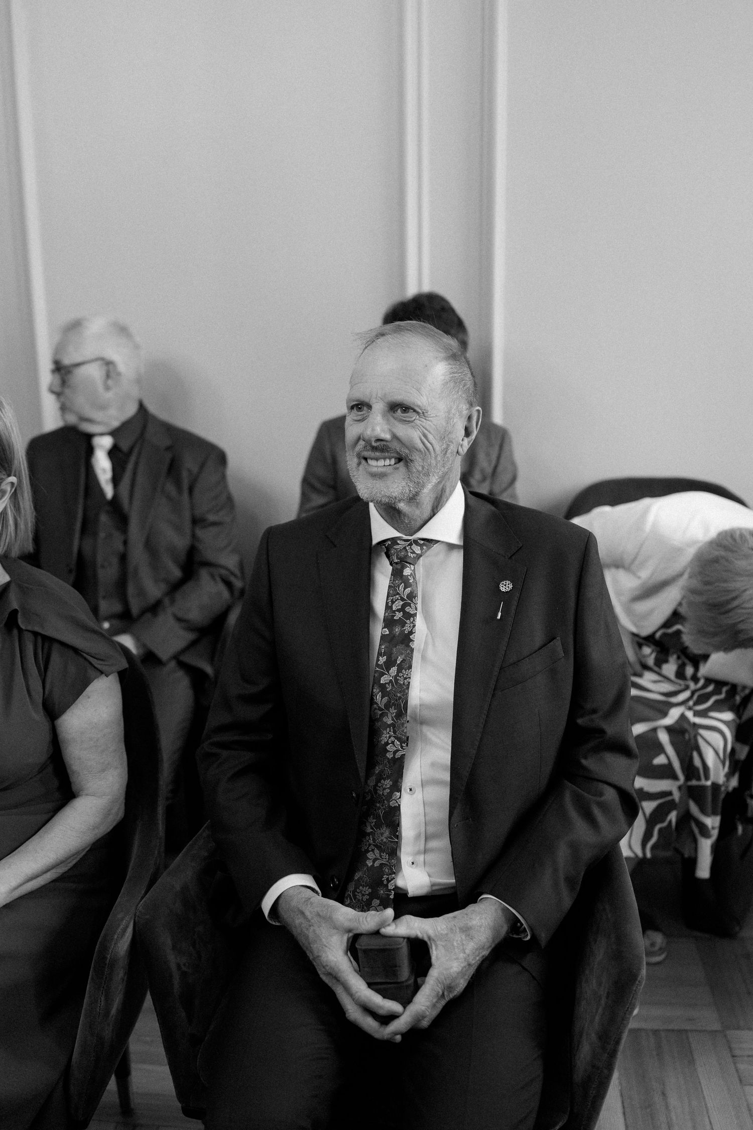Guest in formal attire smiling during wedding celebration in elegant venue.