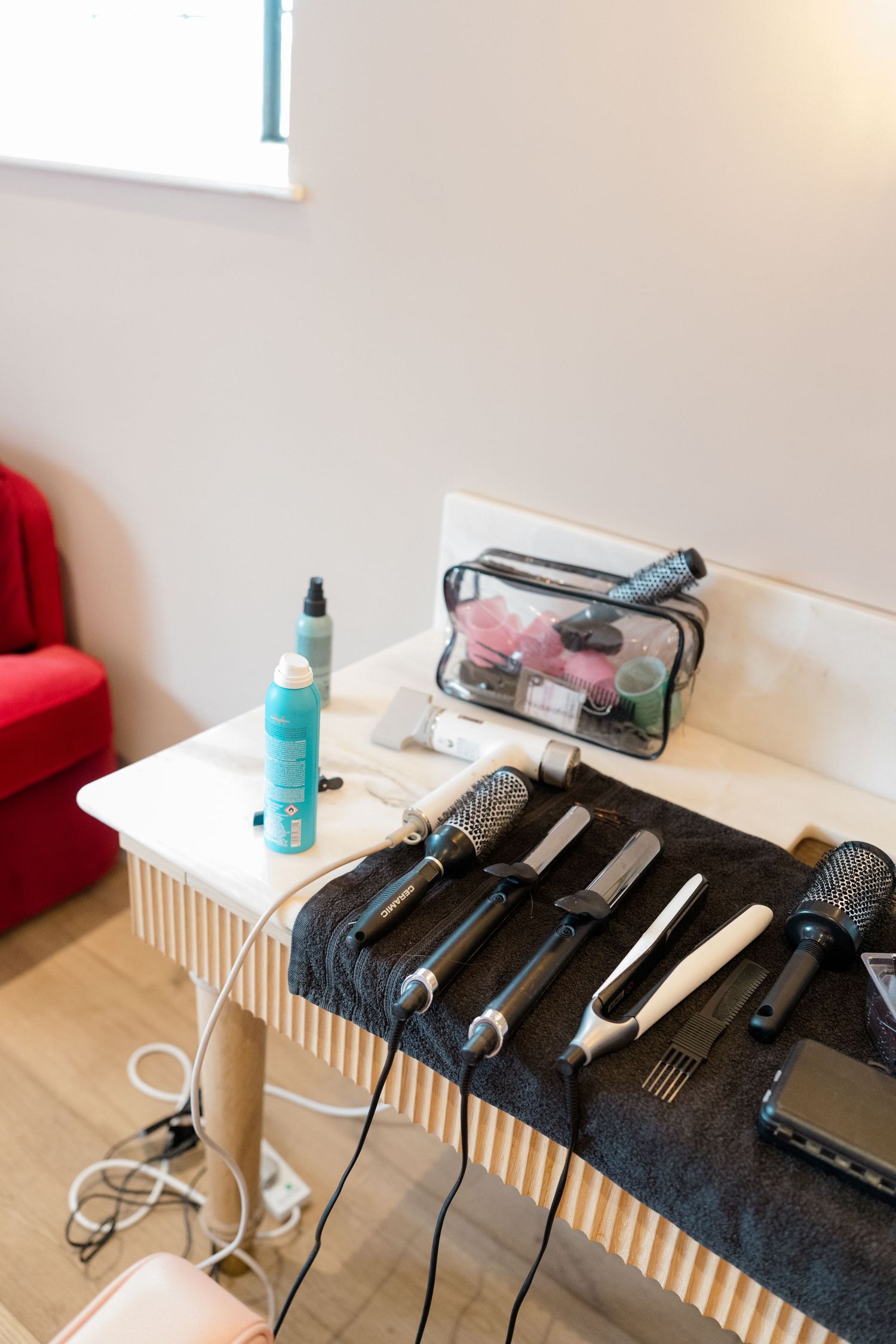 Professional hair styling tools including curling irons and straighteners laid out on a black cloth on a table.