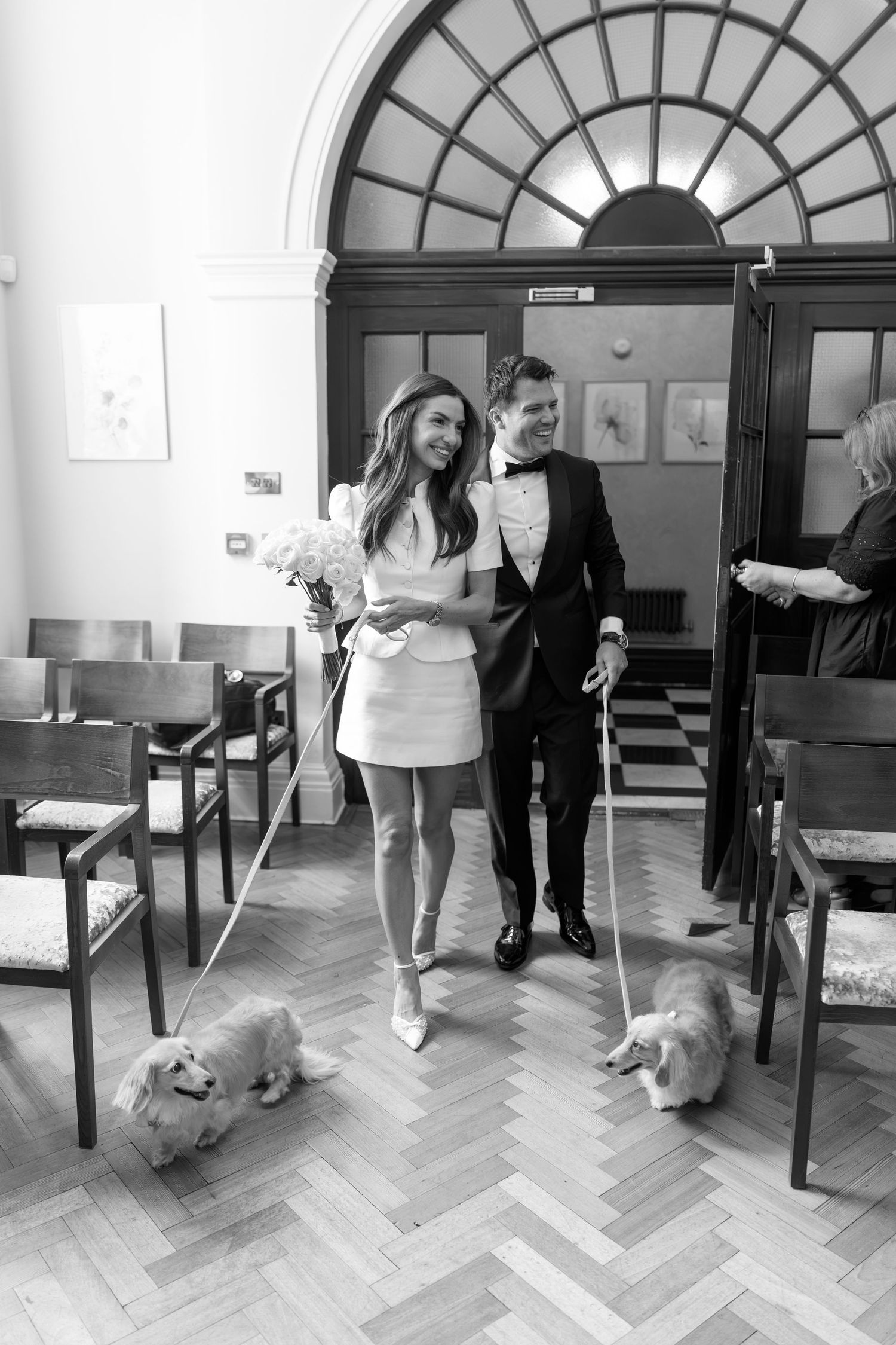 Newlyweds walk down aisle with two corgis in a classic registry office.