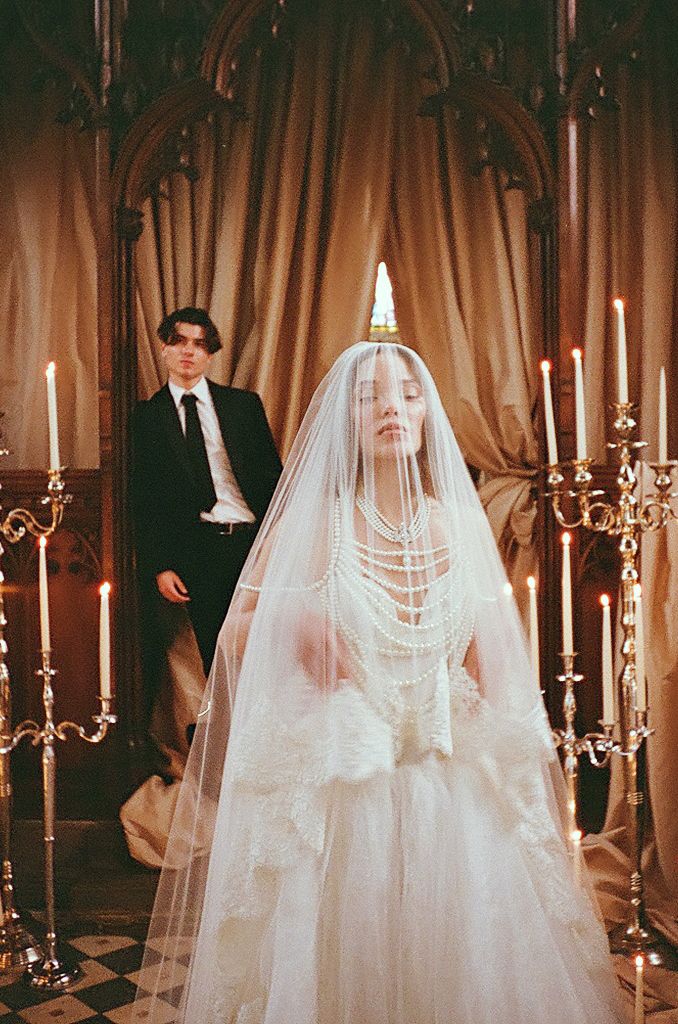 Romantic wedding scene with lit candelabras and flowing white veils in an elegant indoor setting.
