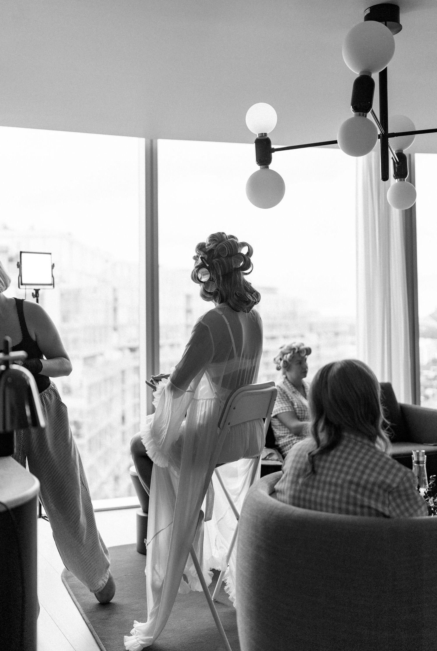 A vintage-style black and white photograph showing people gathered in a room with globe pendant lights.