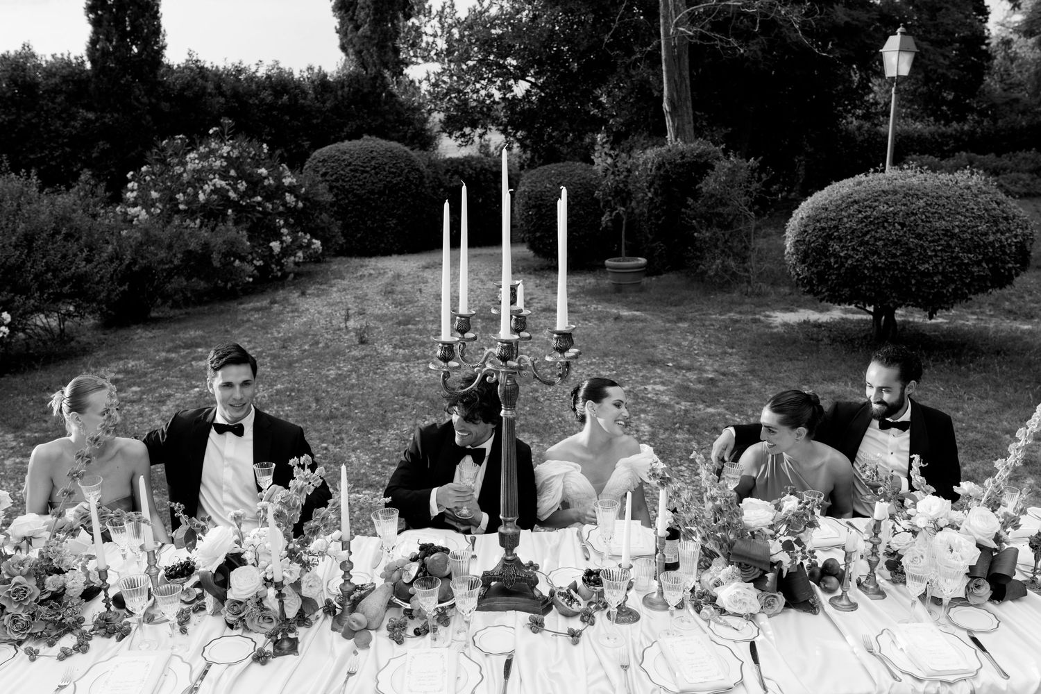 Wedding reception tables set outdoors with white linens and elegant decor.