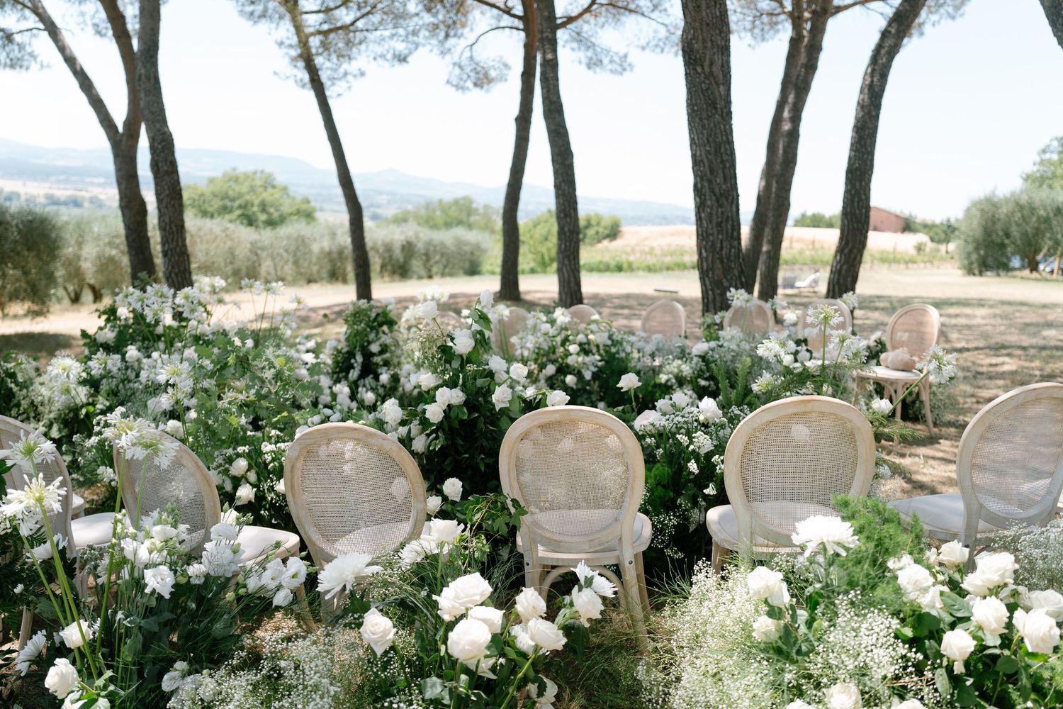 Garden wedding ceremony setup with white floral arrangements and natural greenery.
