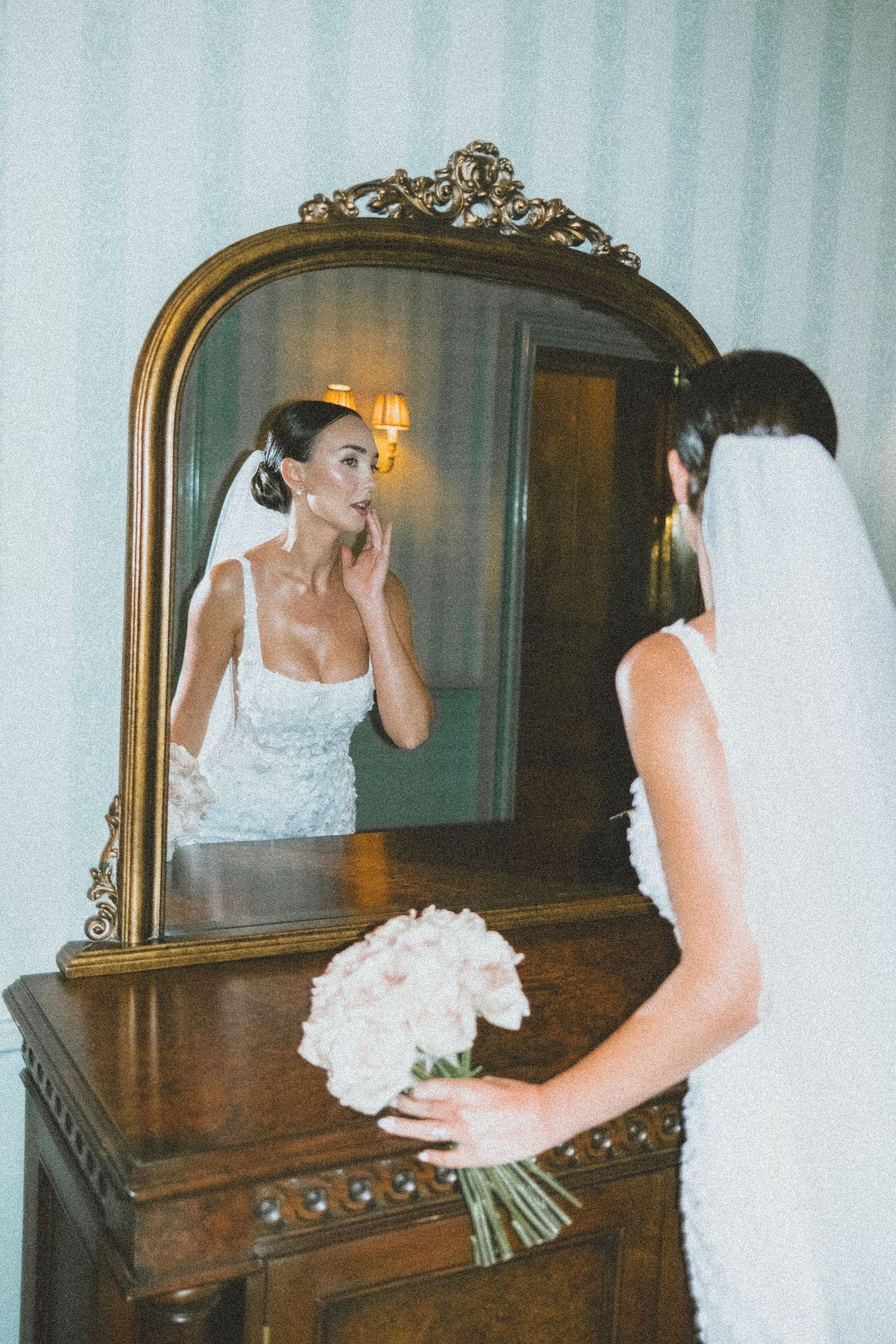 A bride in a white lace dress stands in front of an ornate vintage mirror in three different poses.