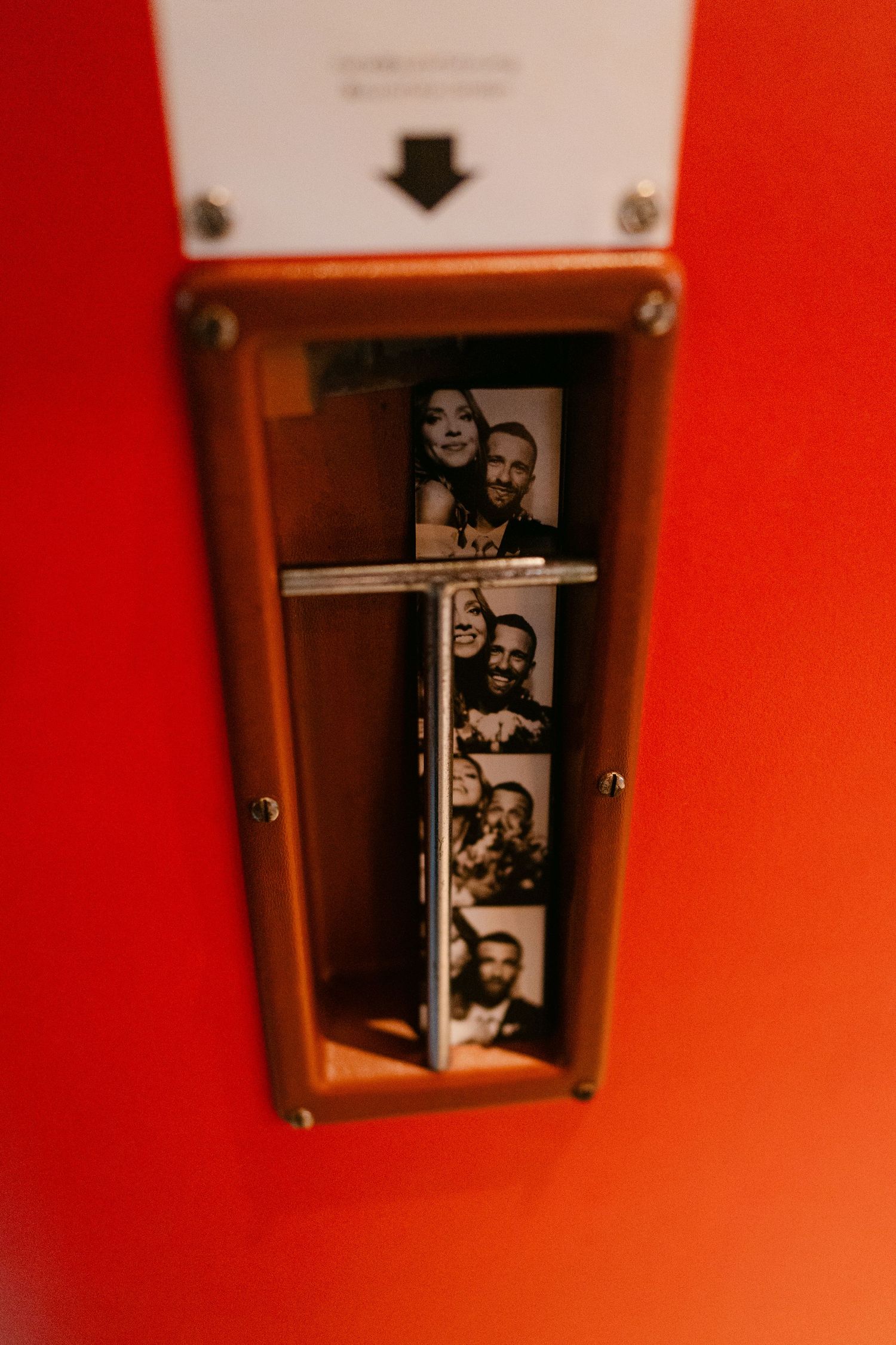 A photo booth strip displayed in a wooden frame mounted on a bright red wall.