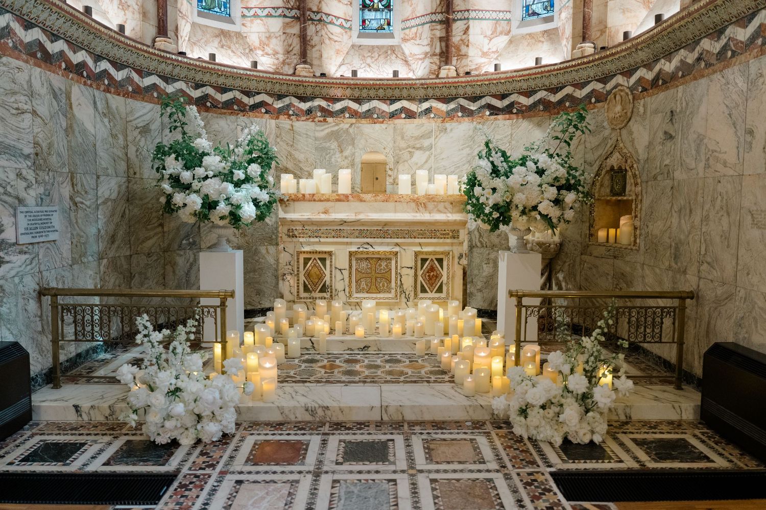 Elegant church altar adorned with white floral arrangements and glowing candles for a wedding ceremony.