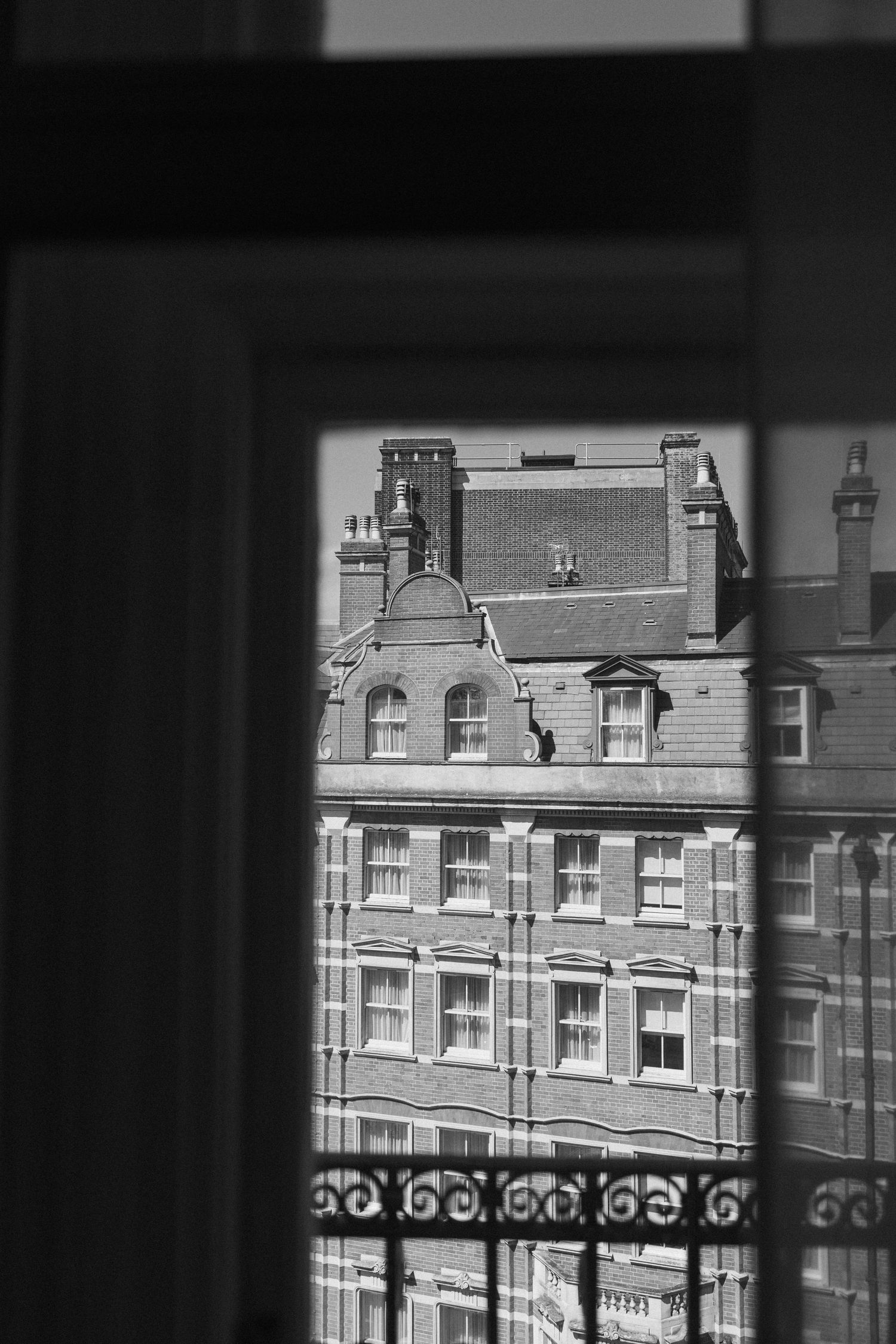 Black and white view through a window of a classic Victorian brick building exterior.