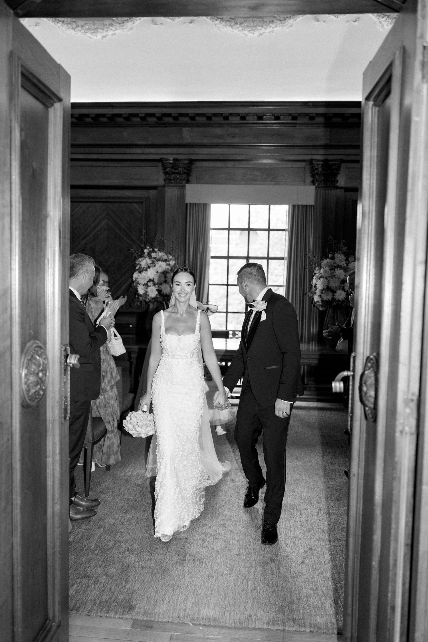 Wedding party members walking through an elegant wood-paneled hallway.