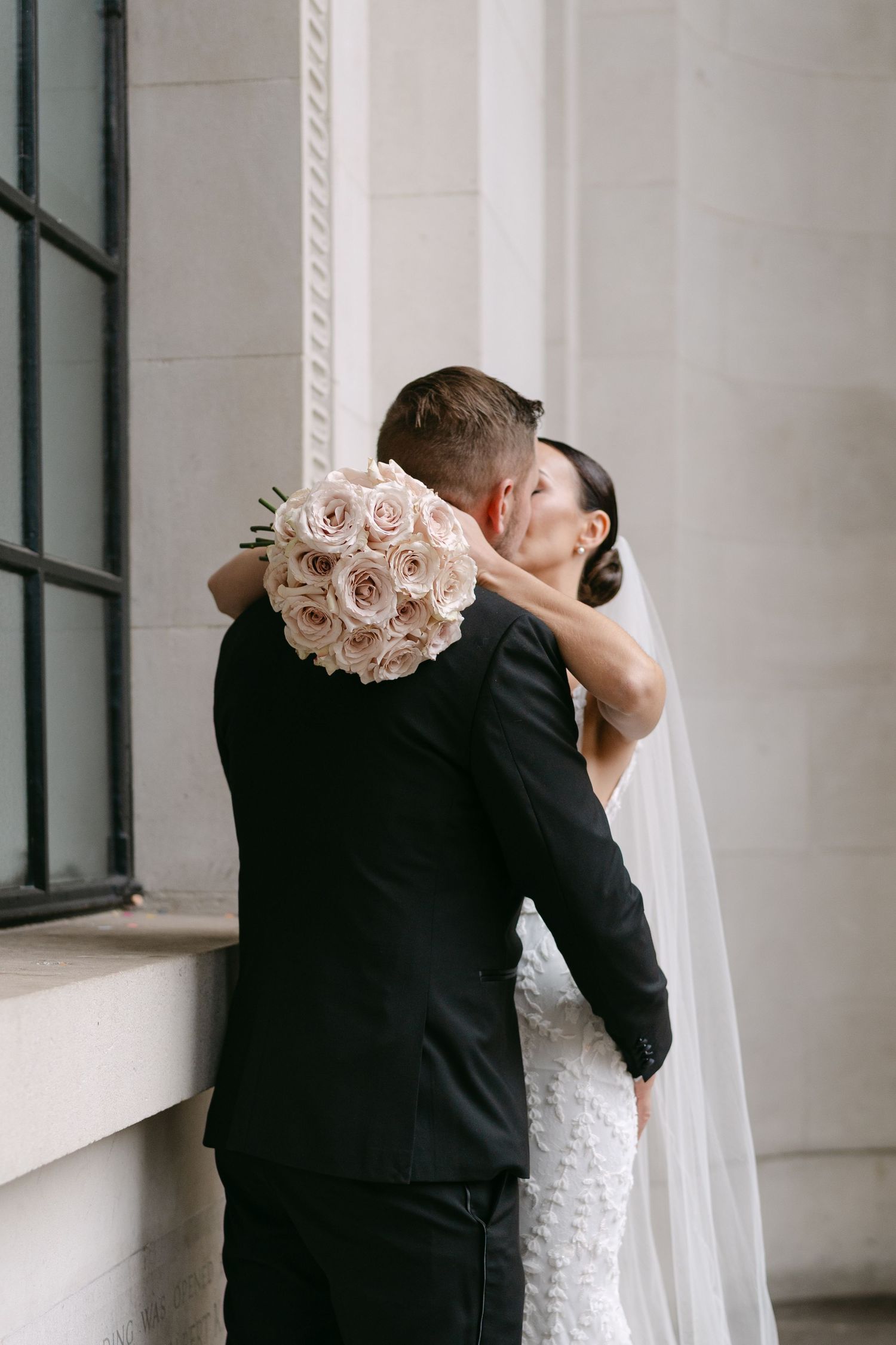 A romantic wedding photo series showing a couple embracing against a classic architectural backdrop.