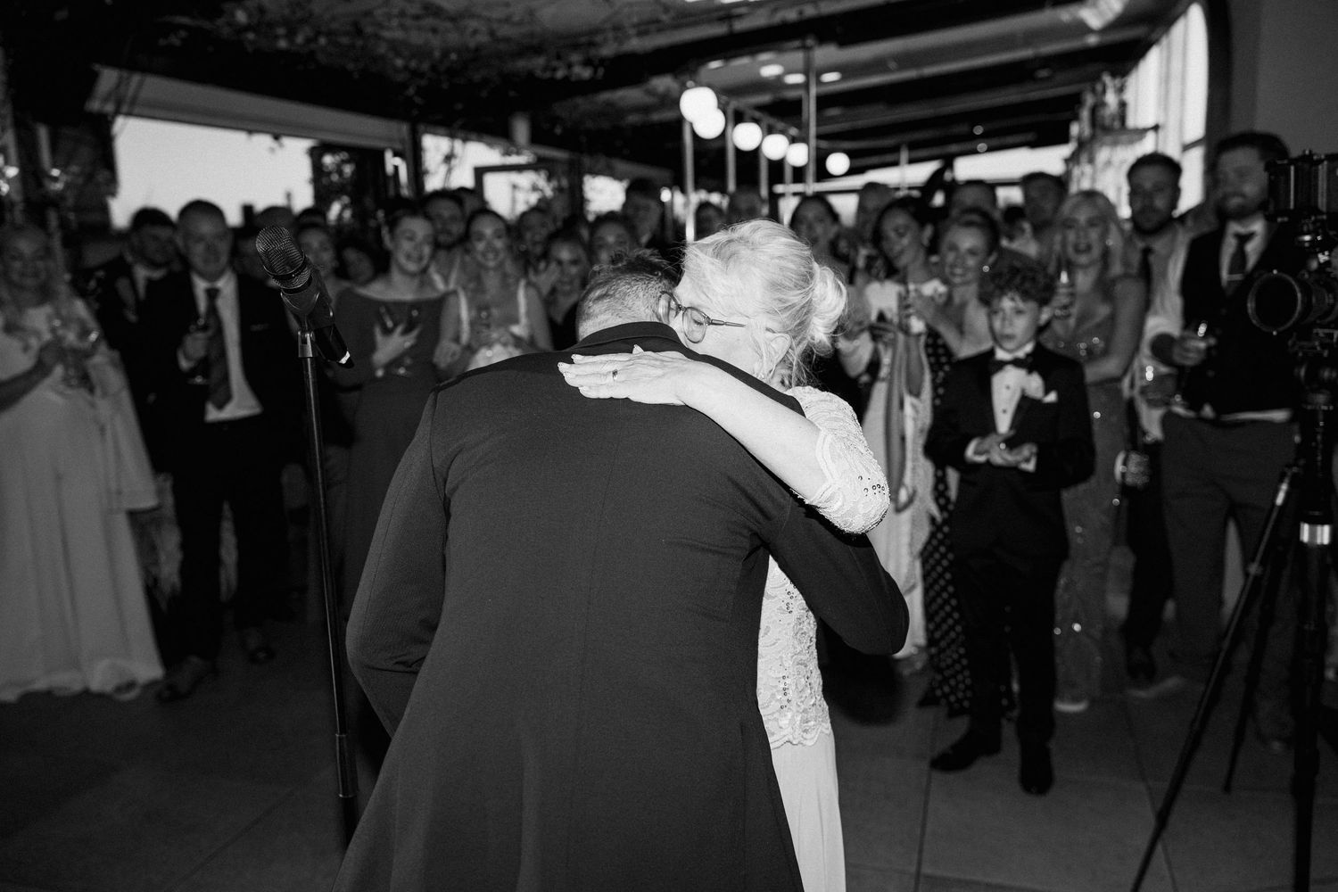 Black and white photo of a romantic first dance at an indoor wedding reception.