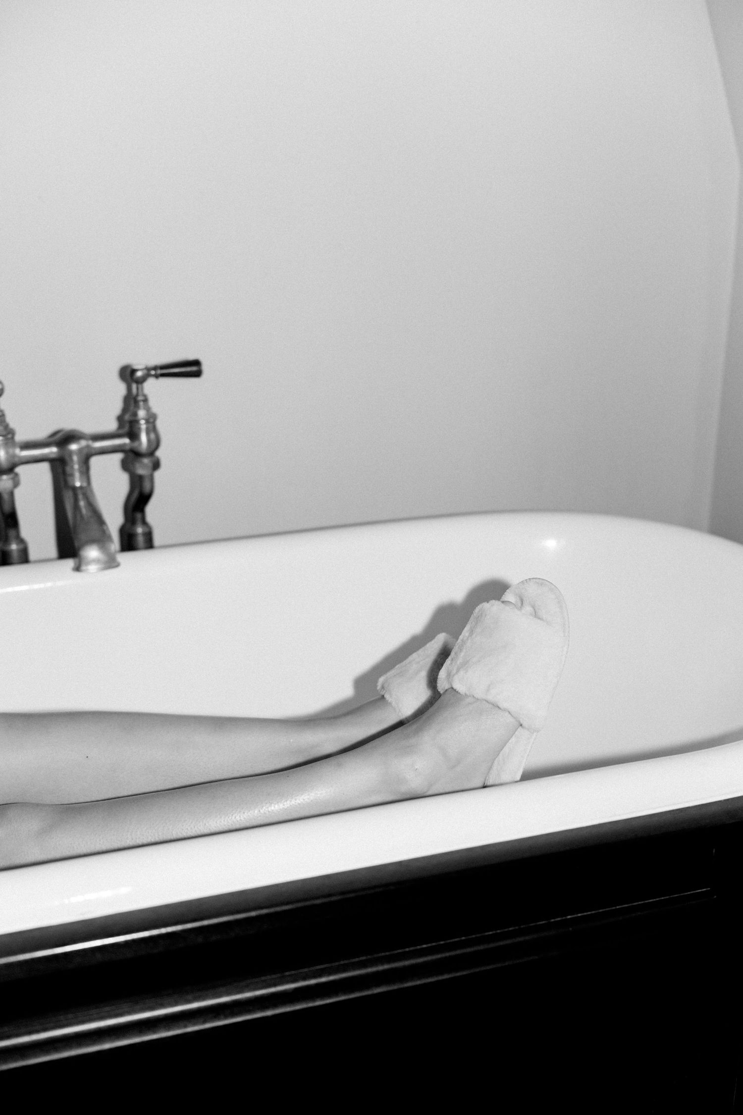 Close-up sequence of a classic clawfoot bathtub with vintage faucets in monochrome.