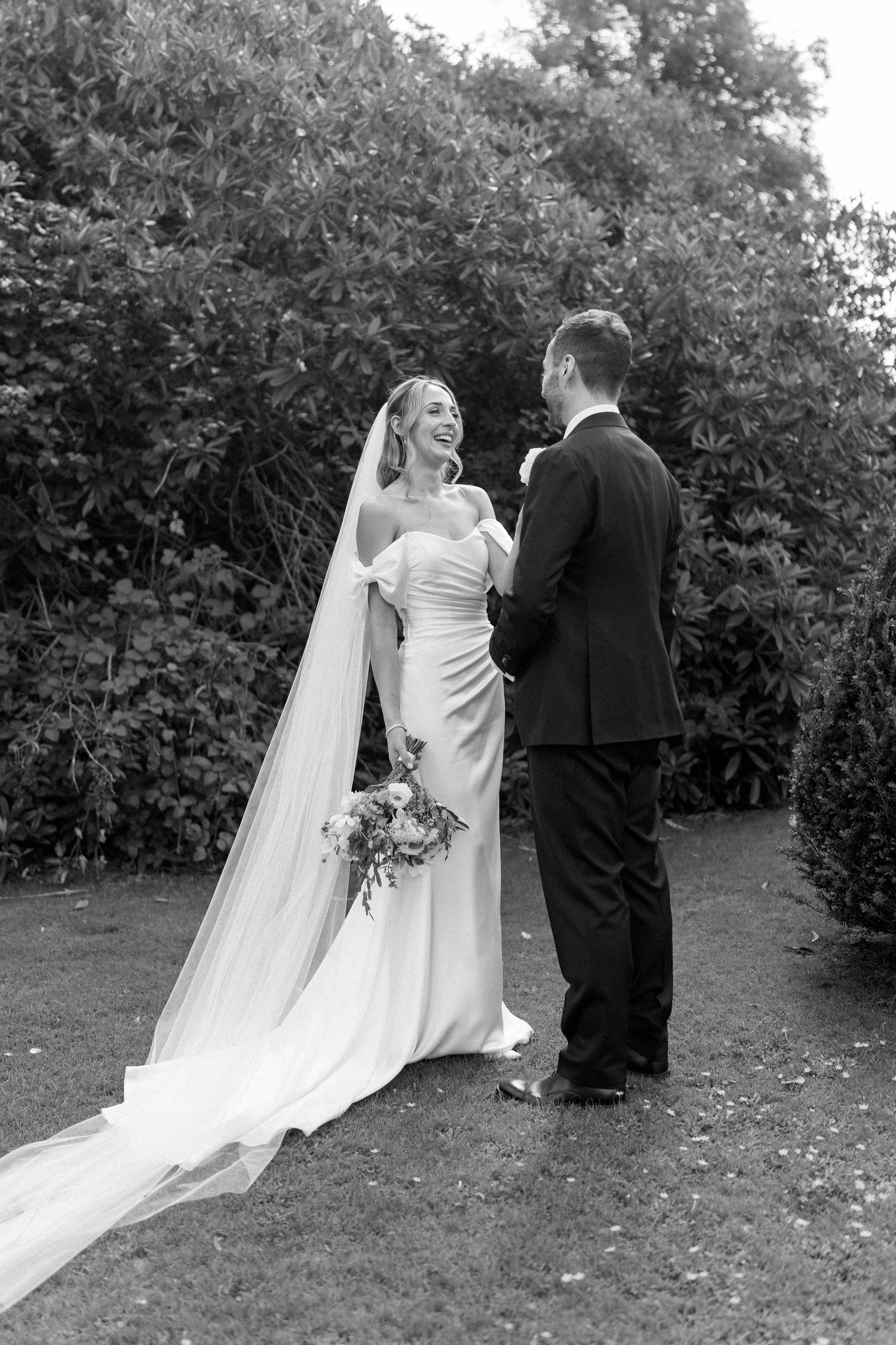 Wedding couple shares an intimate moment in a garden surrounded by greenery.
