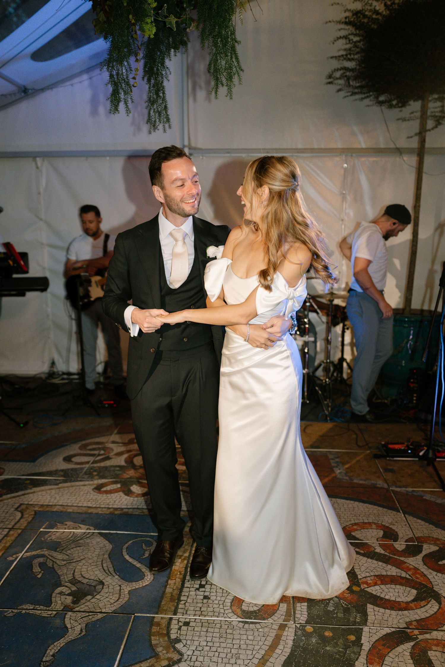 A couple dances together on a decorative floor while a live band performs in the background.