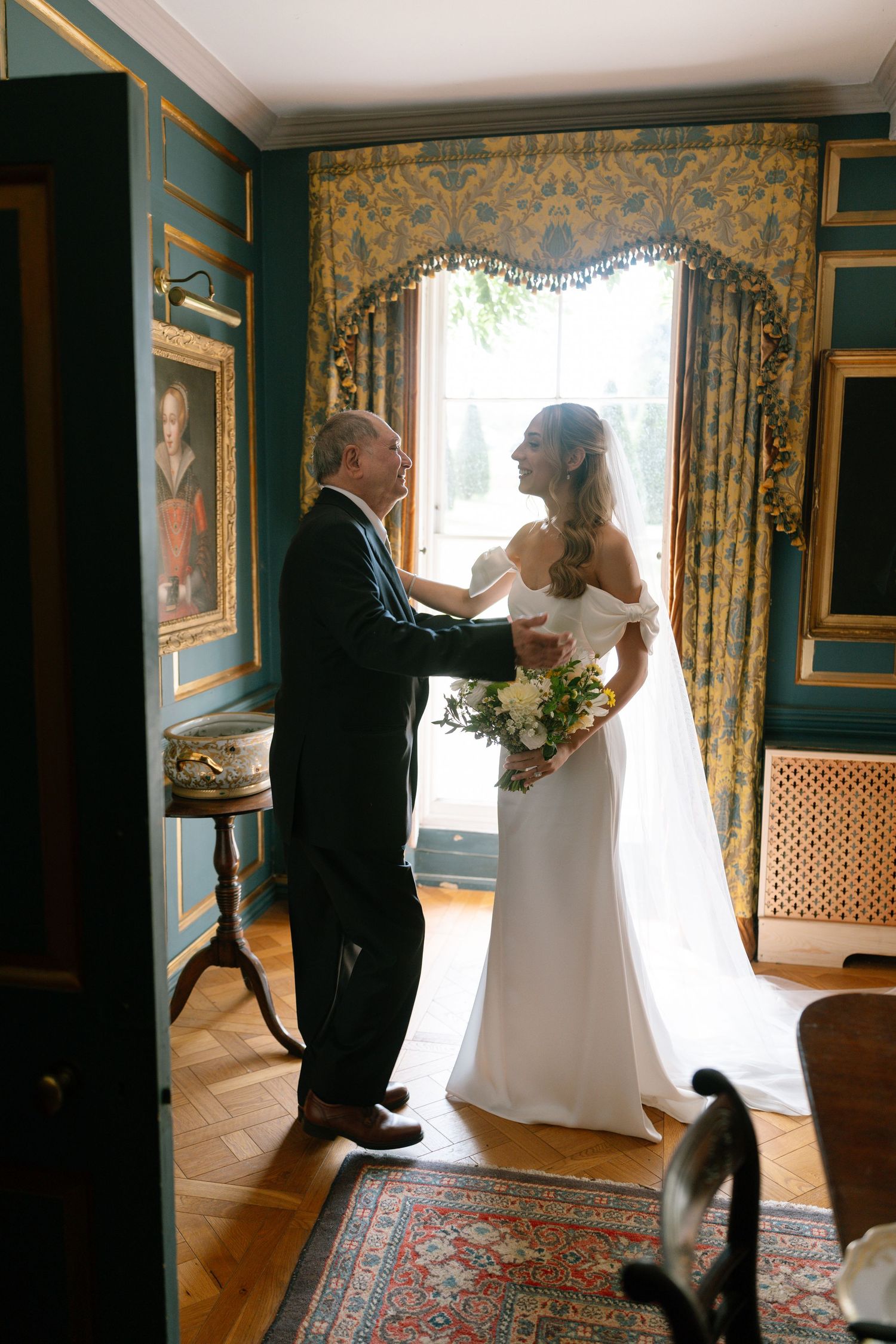 Wedding moment captured in an elegant room with green walls and ornate curtains.